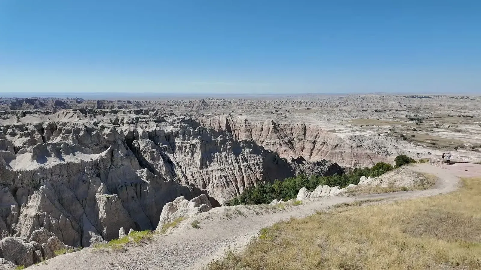 Wide view of eroded Badlands formations and a winding trail from an overlook on the scenic drive