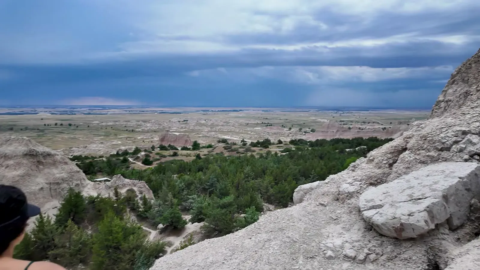 The view from the Notch out over green trees and open plain with dark storm clouds building on the horizon