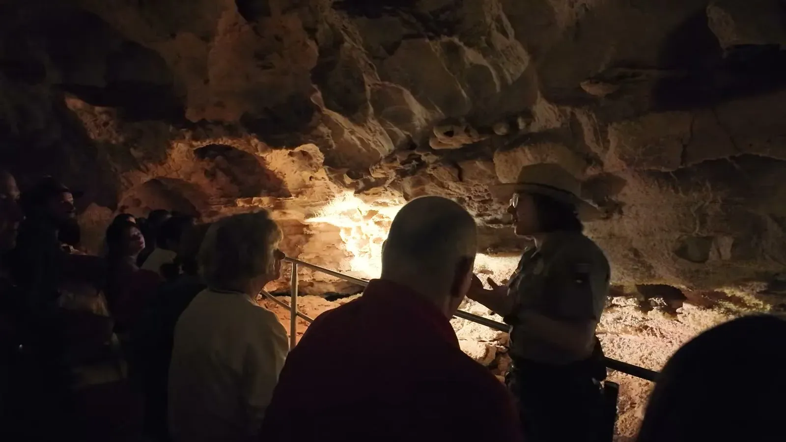 A park ranger in uniform talking to the tour group in a lit chamber deep inside Wind Cave