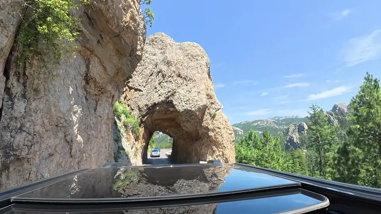 A car passing through the narrow Needle's Eye tunnel cut through a granite spire on the Needles Highway