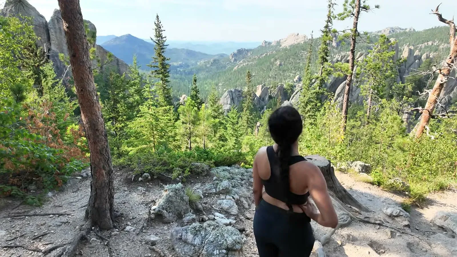 Fabiola on the climb back up, with the granite Needles spires and forested hills opening up behind her