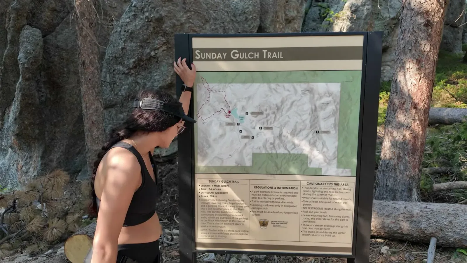 Fabiola reading the Sunday Gulch Trail information sign and map at the trailhead