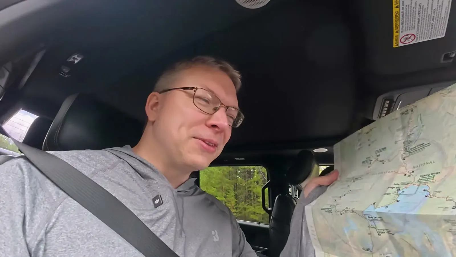 Nathan in the passenger seat holding up the paper Yellowstone park map