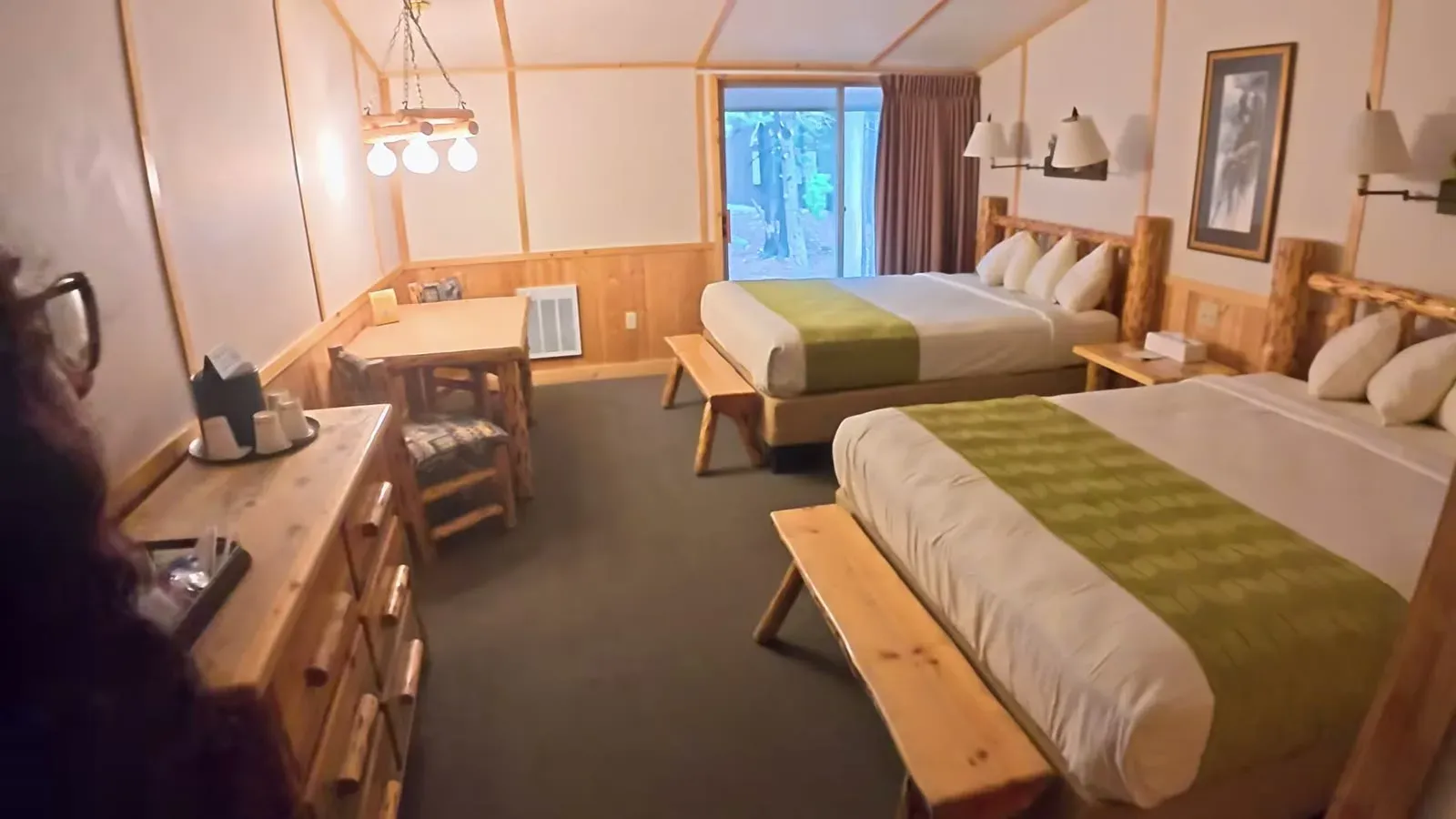 Inside our Canyon cabin: two queen beds with log headboards, green runners and a small table by the window