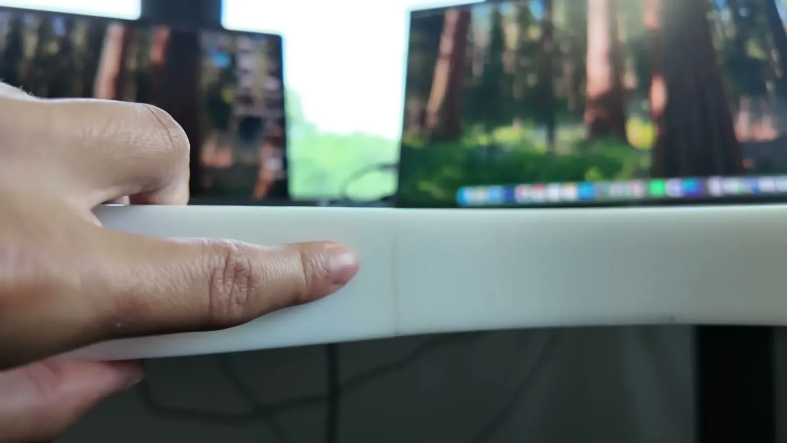 A finger tracing the hairline crack that showed up in the office desk top, monitors blurred in the background.