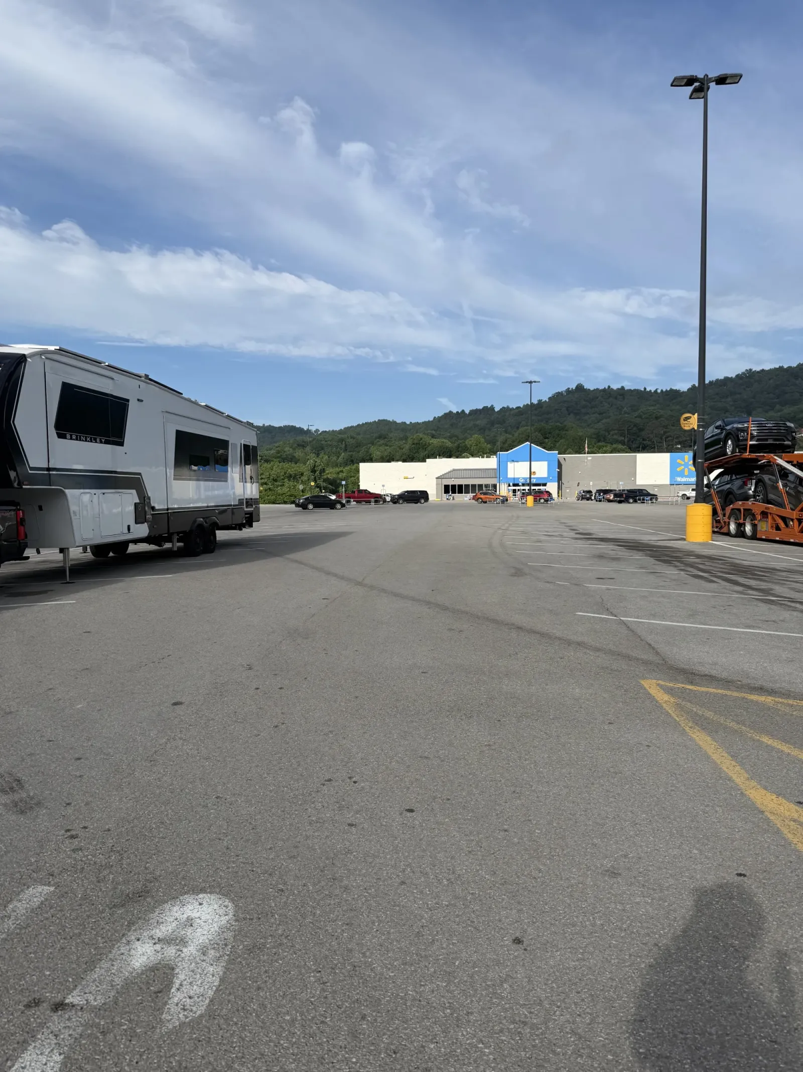 Our Brinkley fifth wheel parked at the edge of the Walmart lot in Williamsburg, Kentucky, with wooded hills behind the store