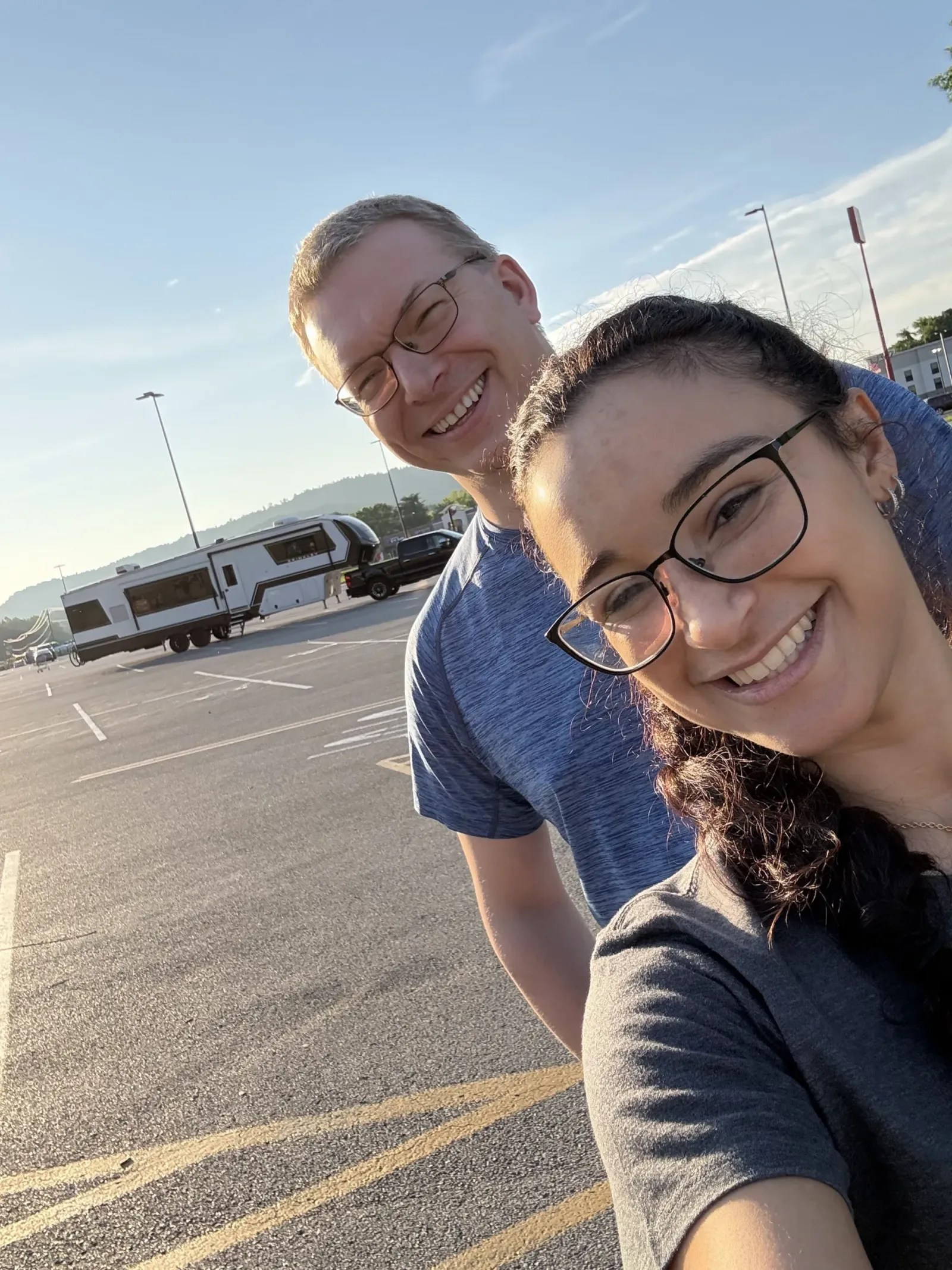 Nathan and Fabiola smiling in the Walmart parking lot in Williamsburg, Kentucky, with their fifth wheel and truck behind them