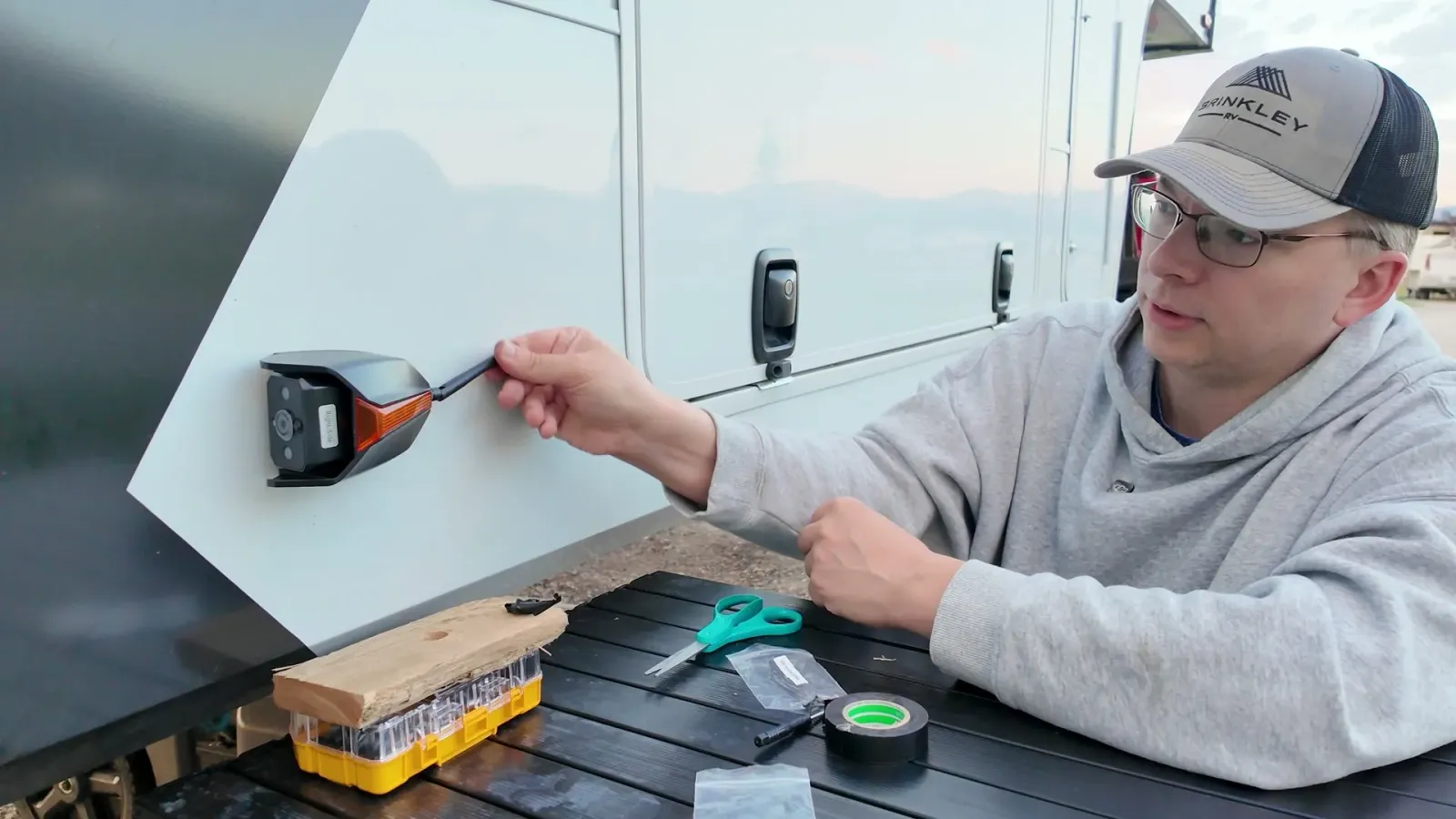 Nathan fitting a CampSync side camera where the marker light used to be on the side of our Brinkley fifth wheel.