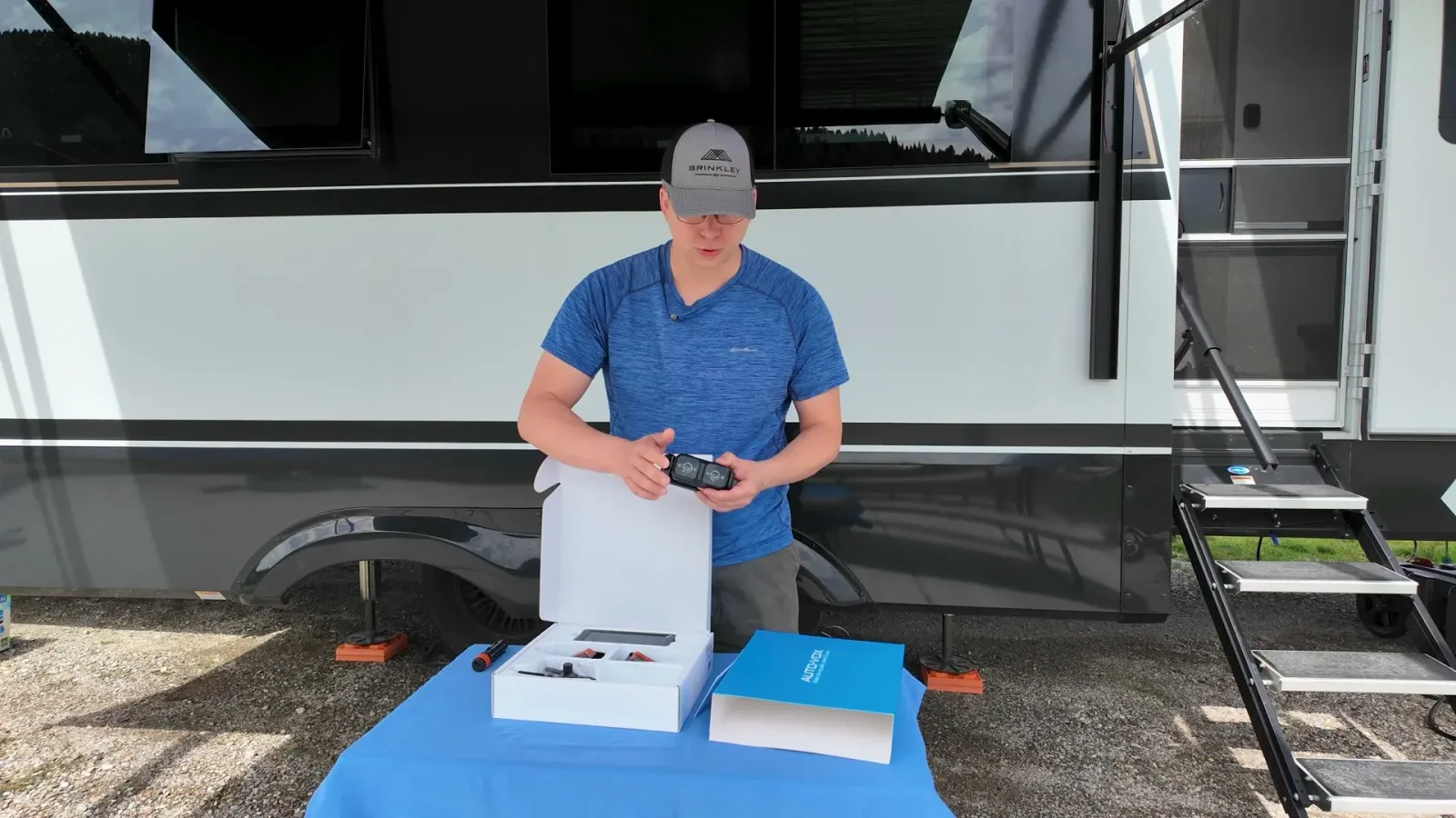 Nathan unboxing the AUTO-VOX CampSync four-camera kit on a table beside our fifth wheel.
