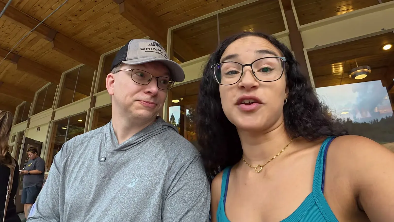 Nathan and Fabiola at lunch under a wooden porch roof, in the middle of the hot dog debate