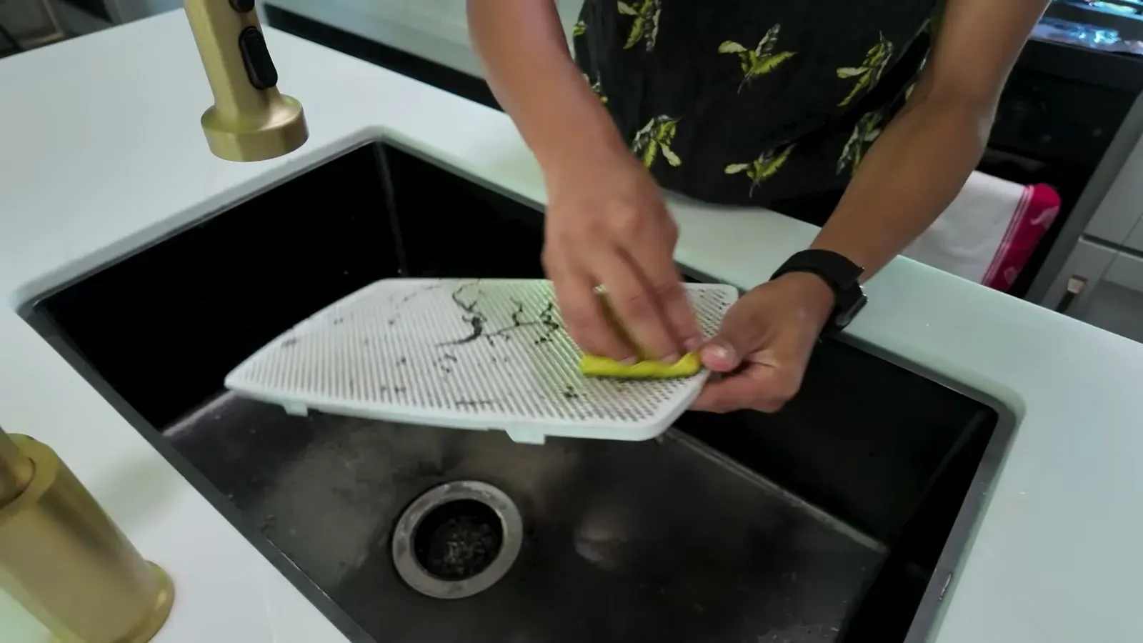 Scrubbing the dusty AC filter screen with a sponge over the kitchen sink in our Brinkley.