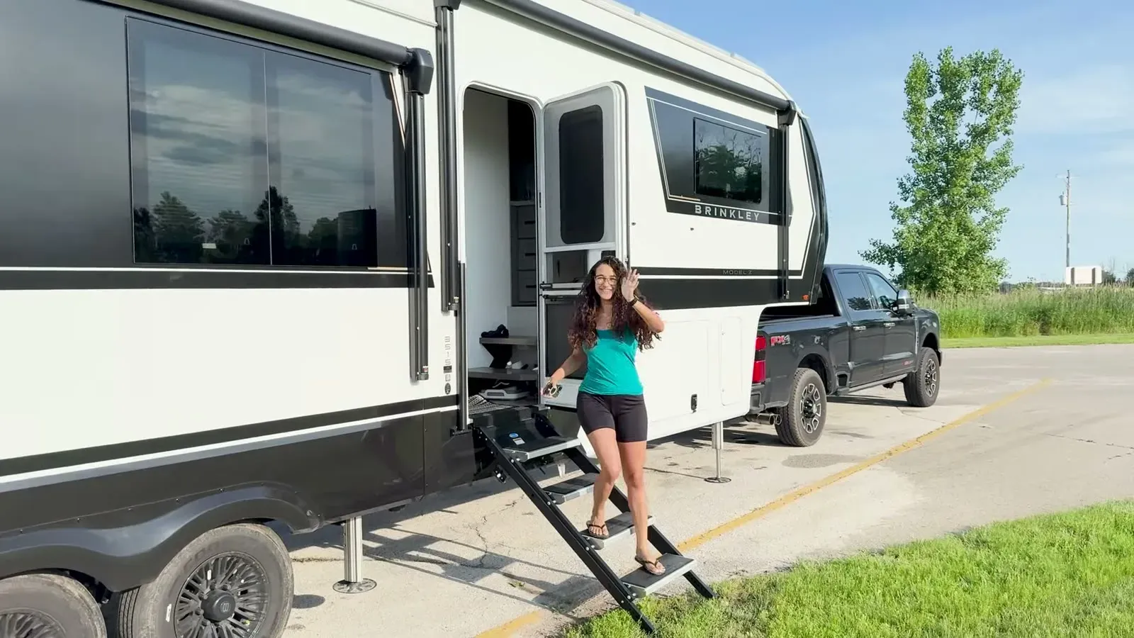 Fabiola waves from the steps with the Brinkley already hitched to the truck on a sunny travel day.