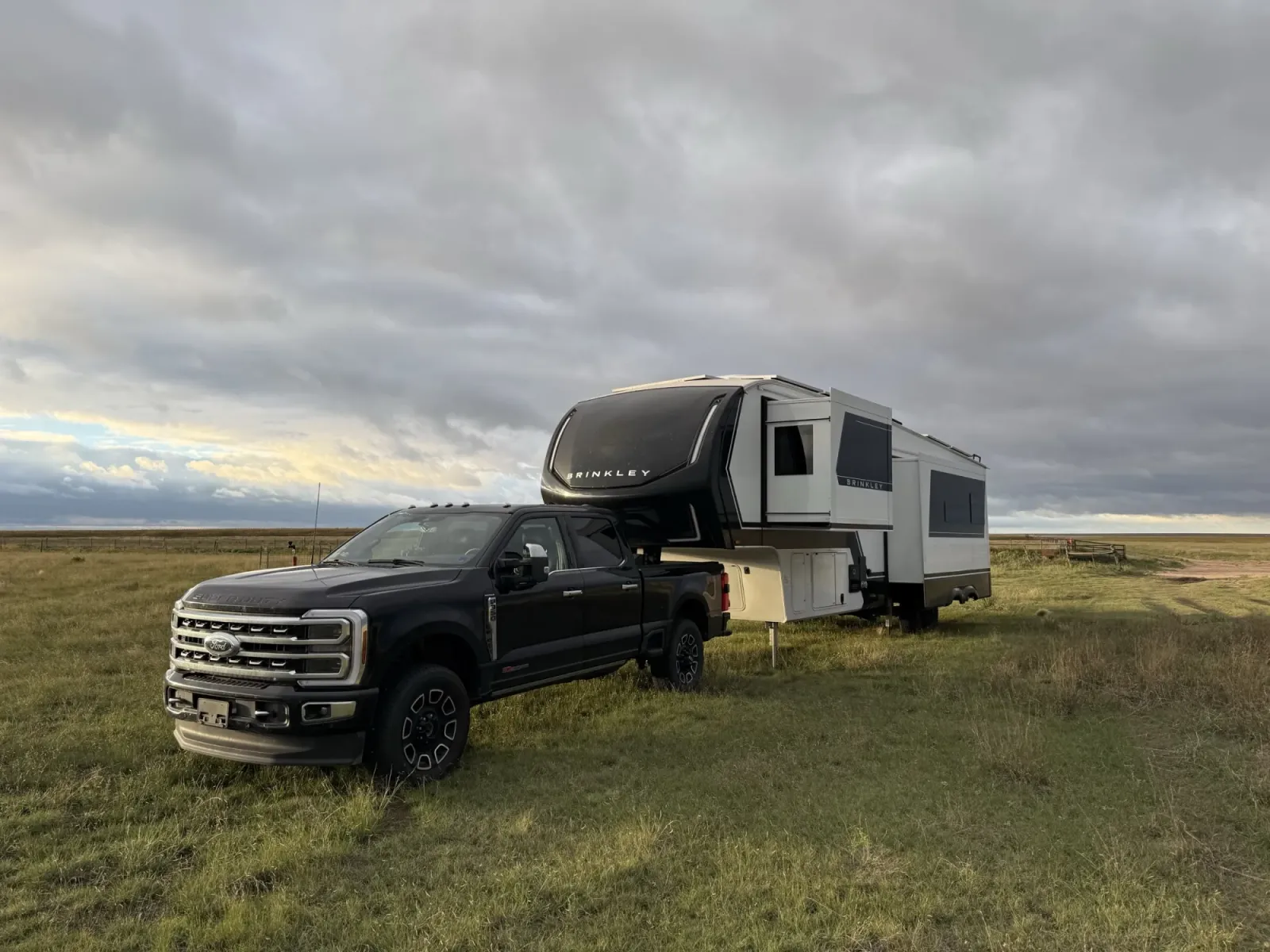 Our F-350 still hitched to the Brinkley on open grassland under a cloudy sky, with the slides out