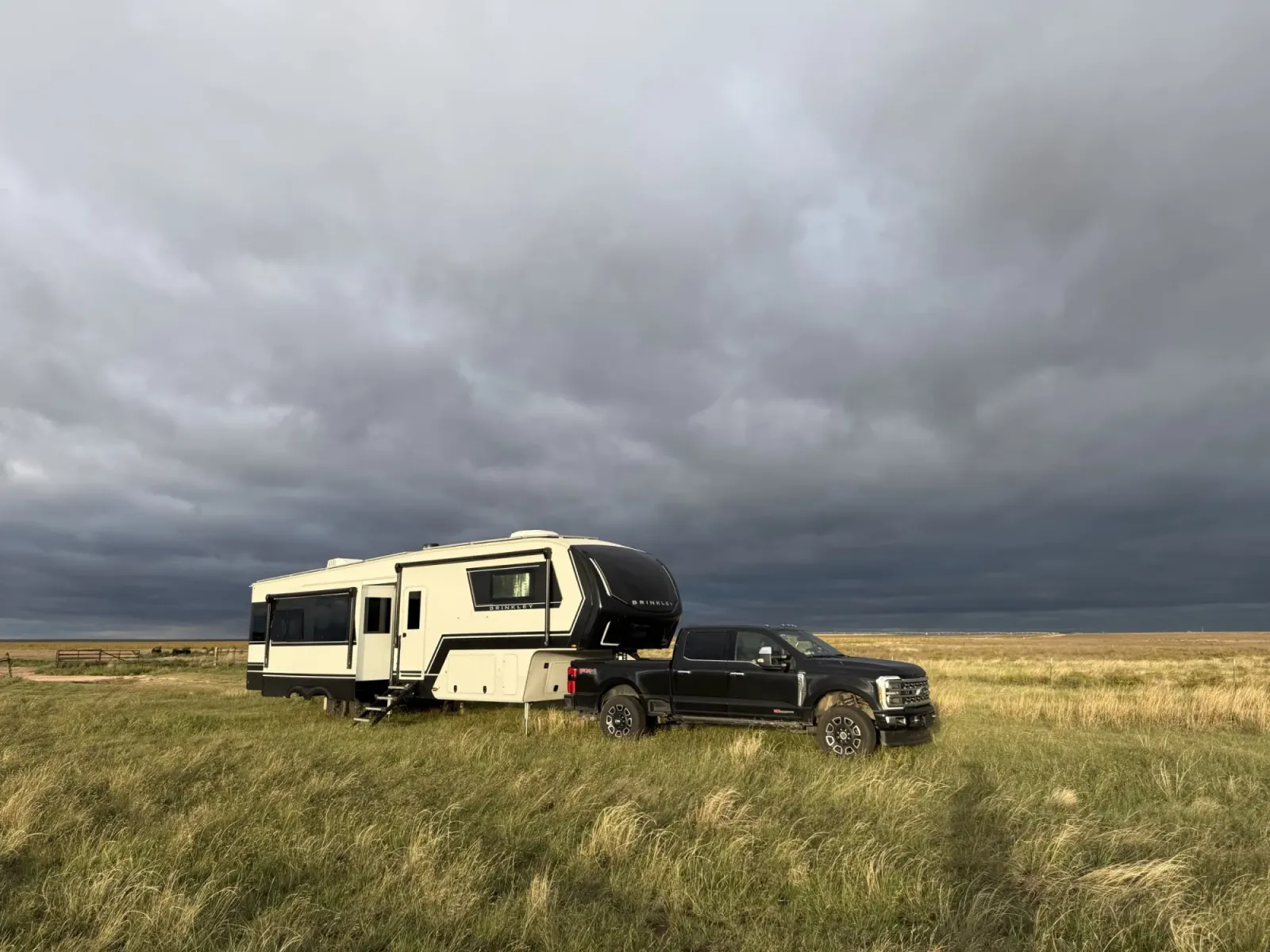 Our Brinkley Model Z 3515 fifth wheel hitched to our black Ford F-350 on open grassland under dark storm clouds