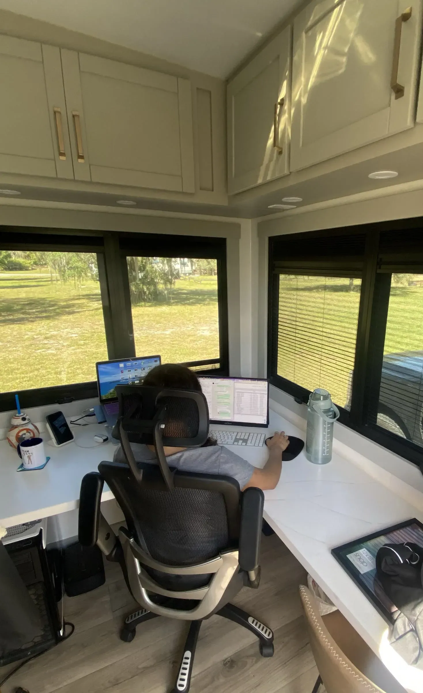 Working at the corner desk in the rear office of our Brinkley Model Z 3515, in a rolling office chair, with windows on two sides