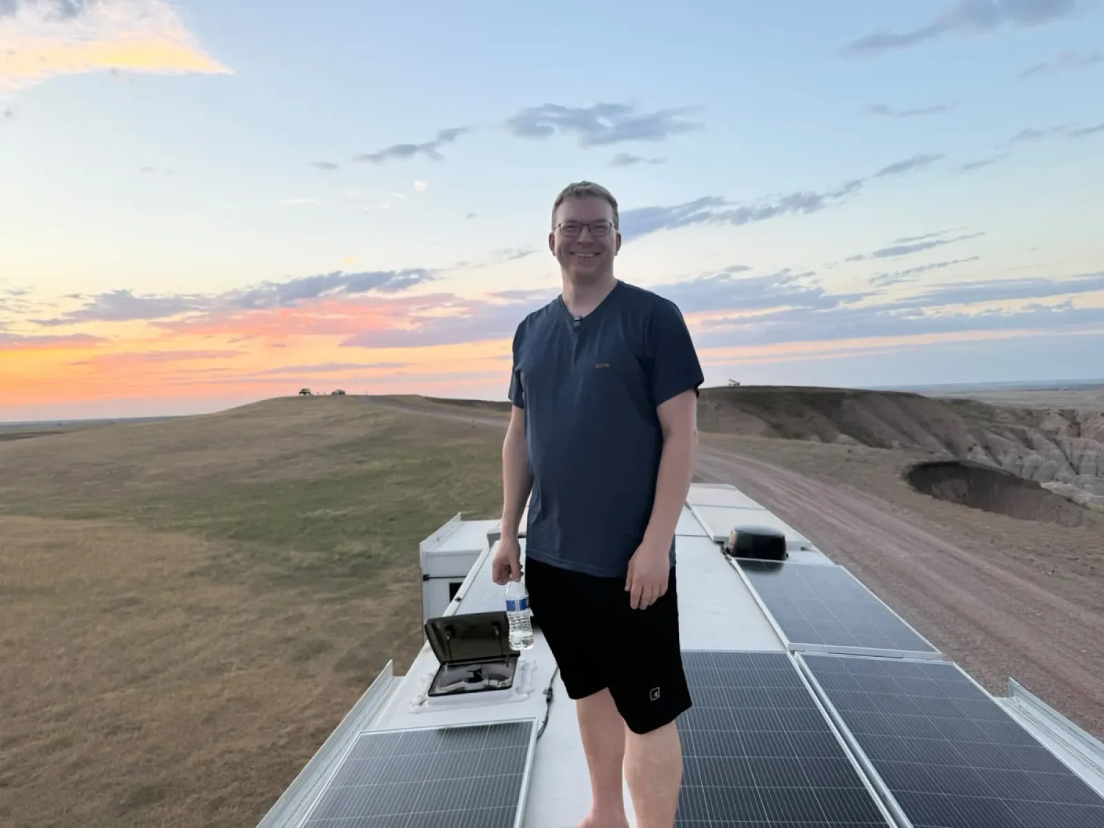 Nathan standing on the roof of our Brinkley between rows of 200 watt solar panels at sunset