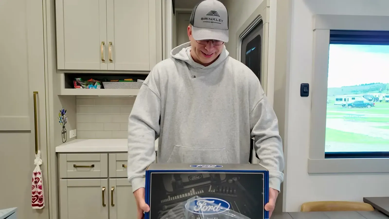 Nathan in the RV kitchen lifting a Ford-branded toolkit box onto the counter
