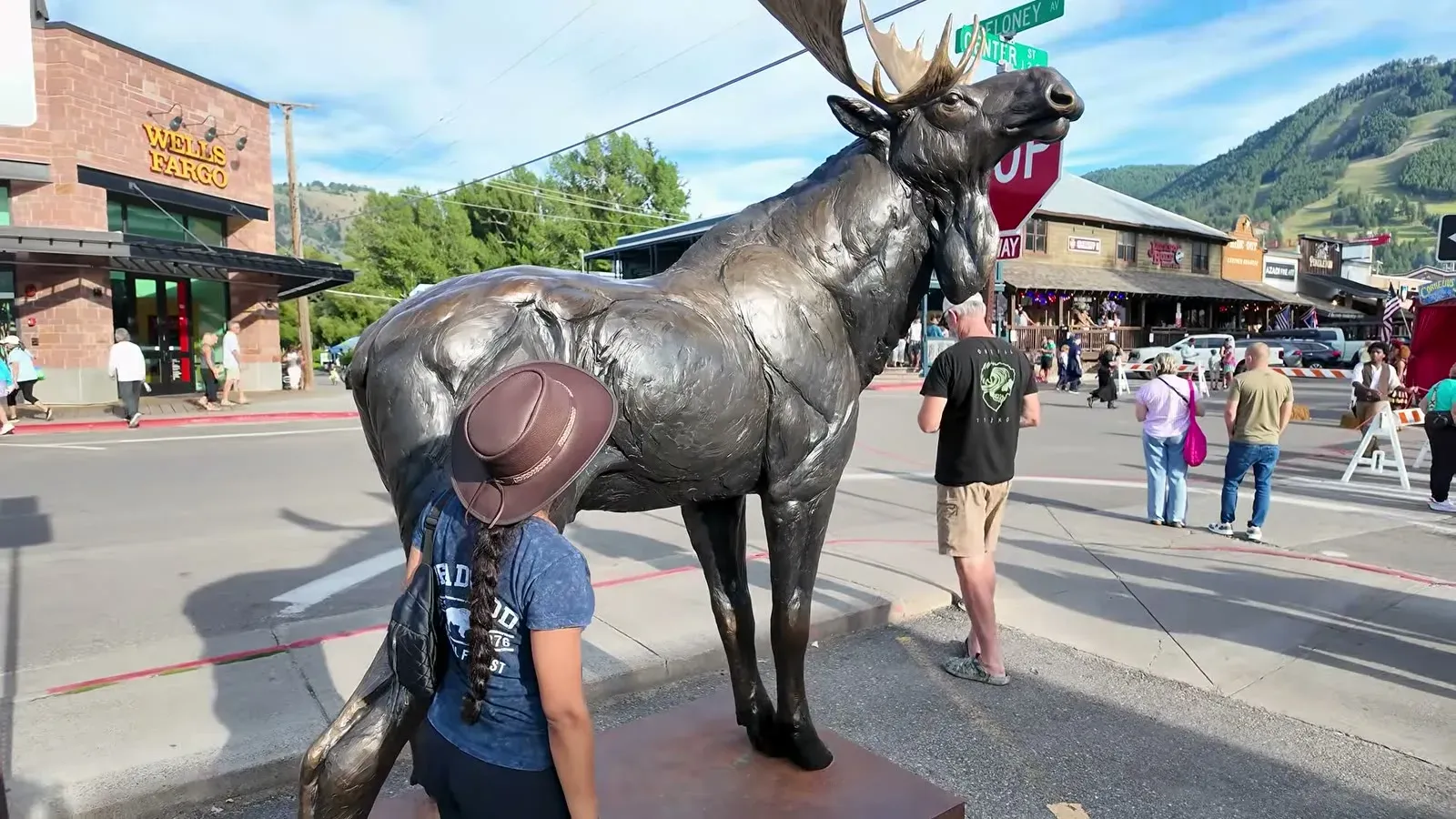 Fabiola in her new cowboy hat beside a bronze moose statue on a busy street corner in downtown Jackson