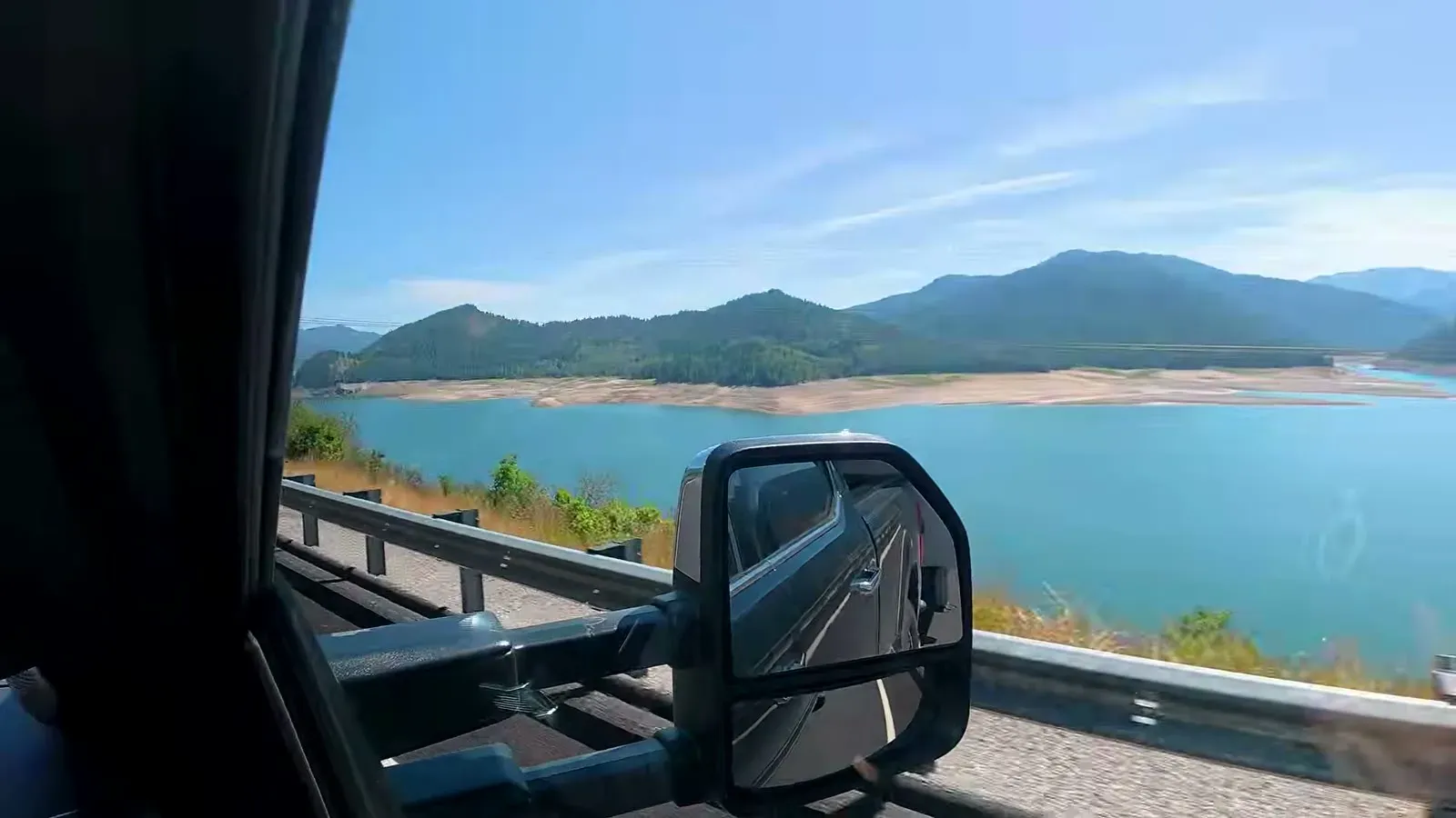 A blue mountain reservoir seen past the truck's tow mirror on our drive toward Jackson Hole