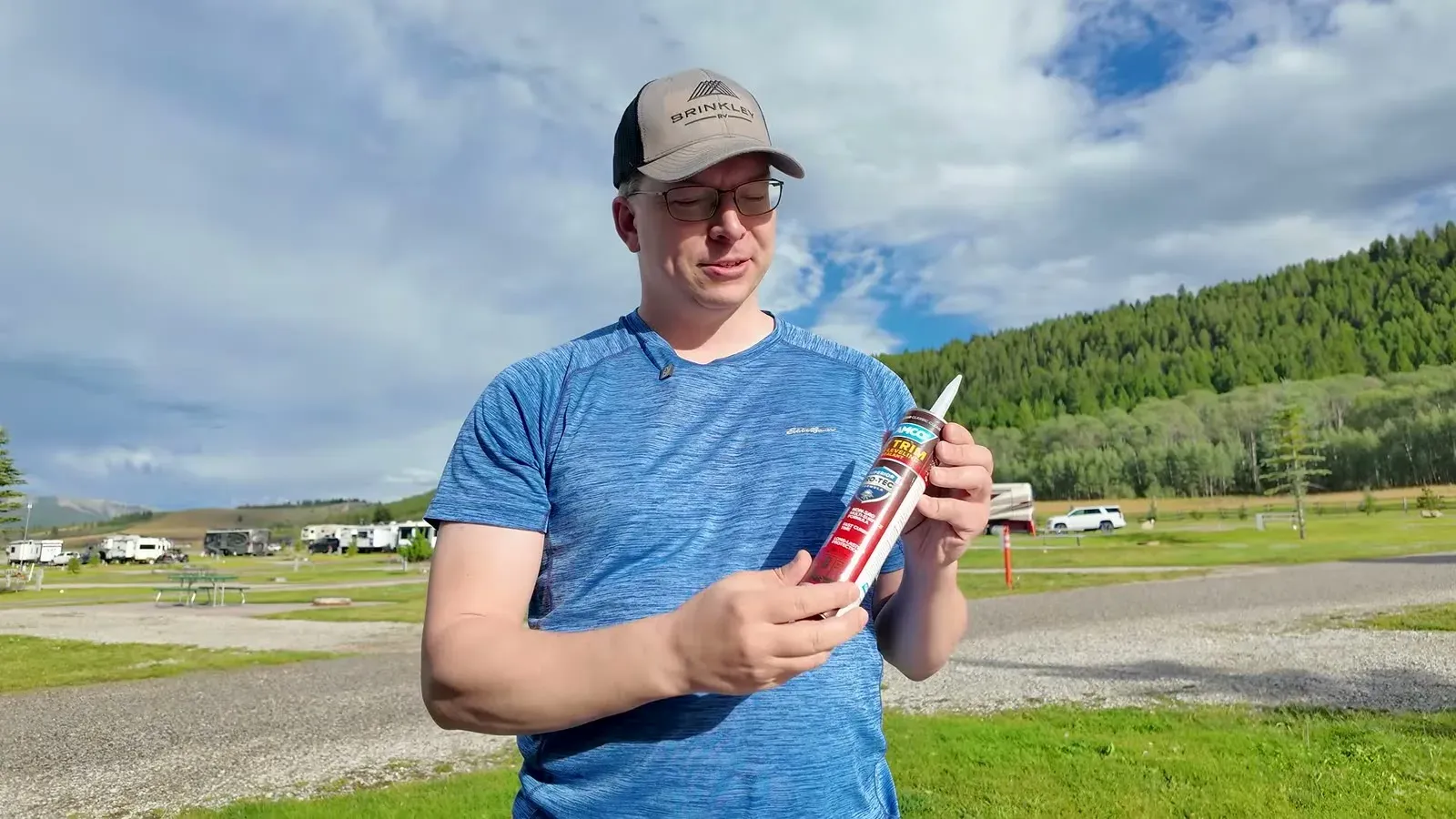 Nathan at the campground holding the tube of sealant he brought back from the hardware store