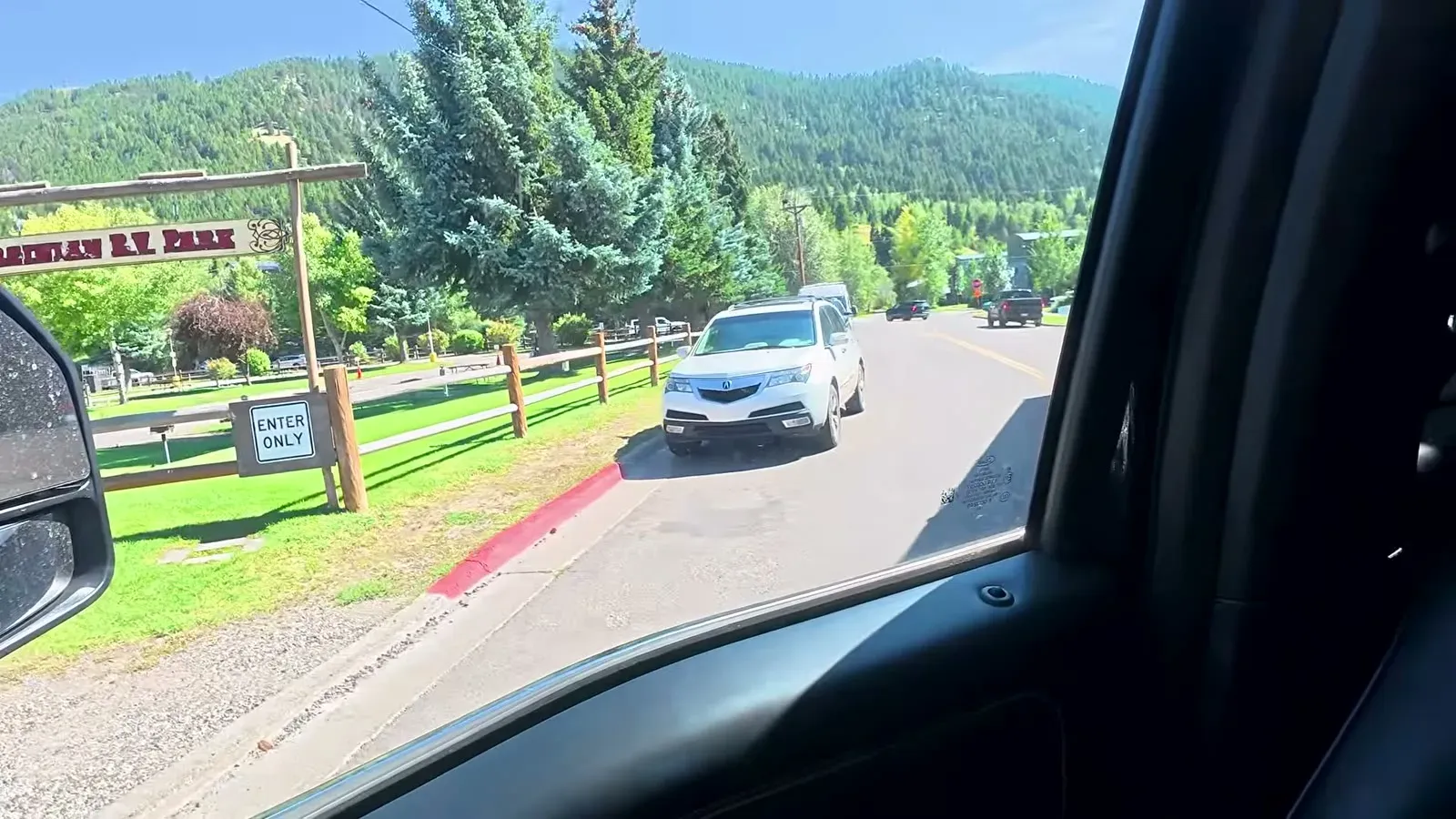 Pulling up to the wooden entrance sign of Virginian RV Park in Jackson Hole, with pine-covered hills behind it