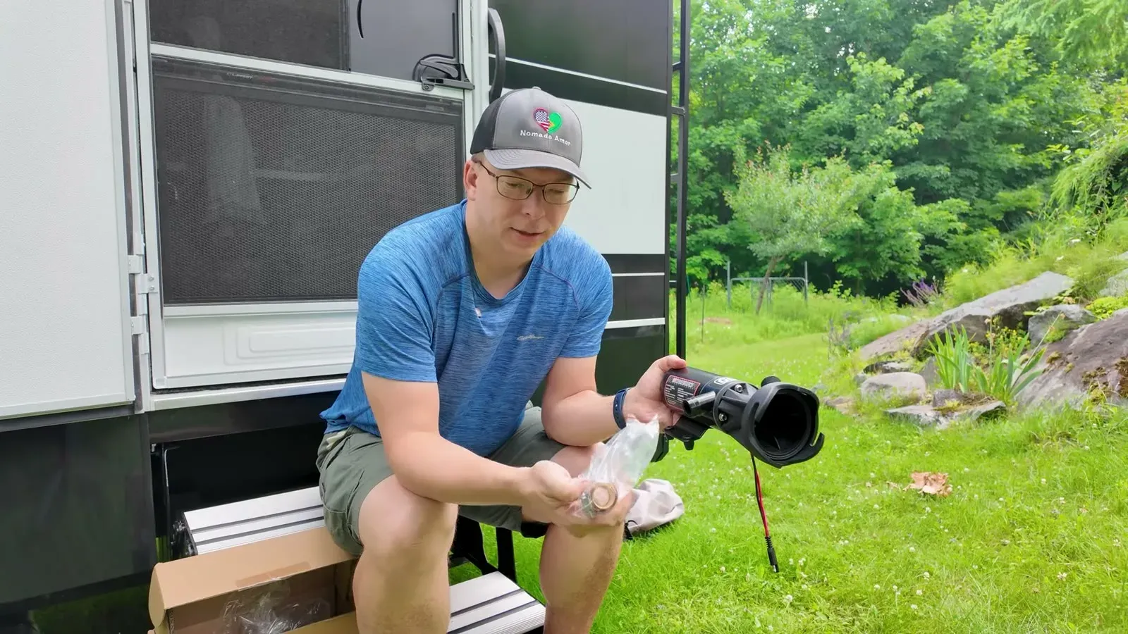 Nathan sits on the RV steps unpacking the 12V macerator pump for the first time.