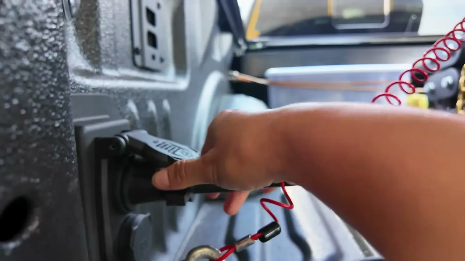 Plugging the seven-pin trailer connector back into the truck's bed socket on the shoulder.