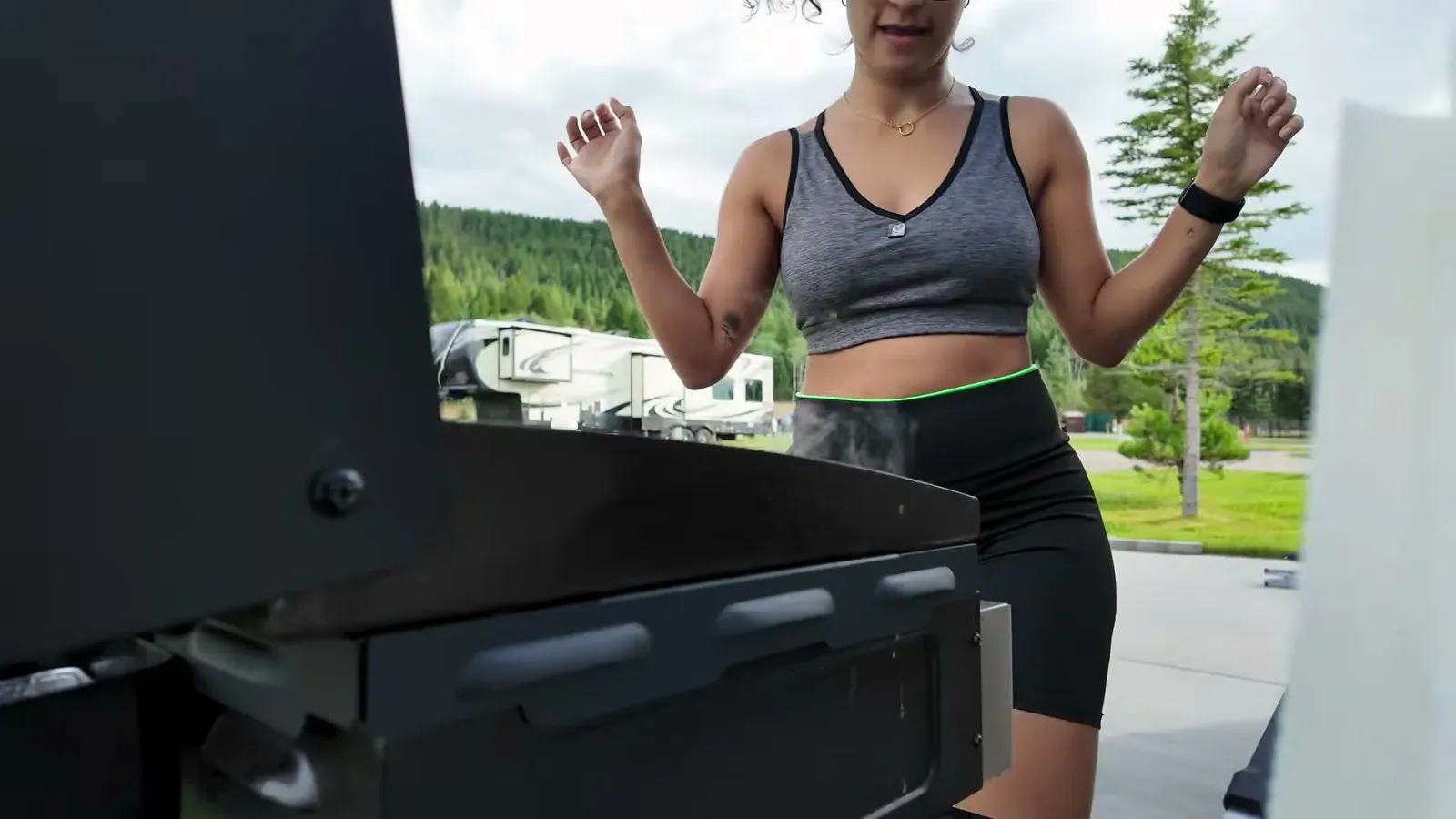 Fabiola celebrating behind the Blackstone griddle with the new wind guards on, outside our fifth wheel