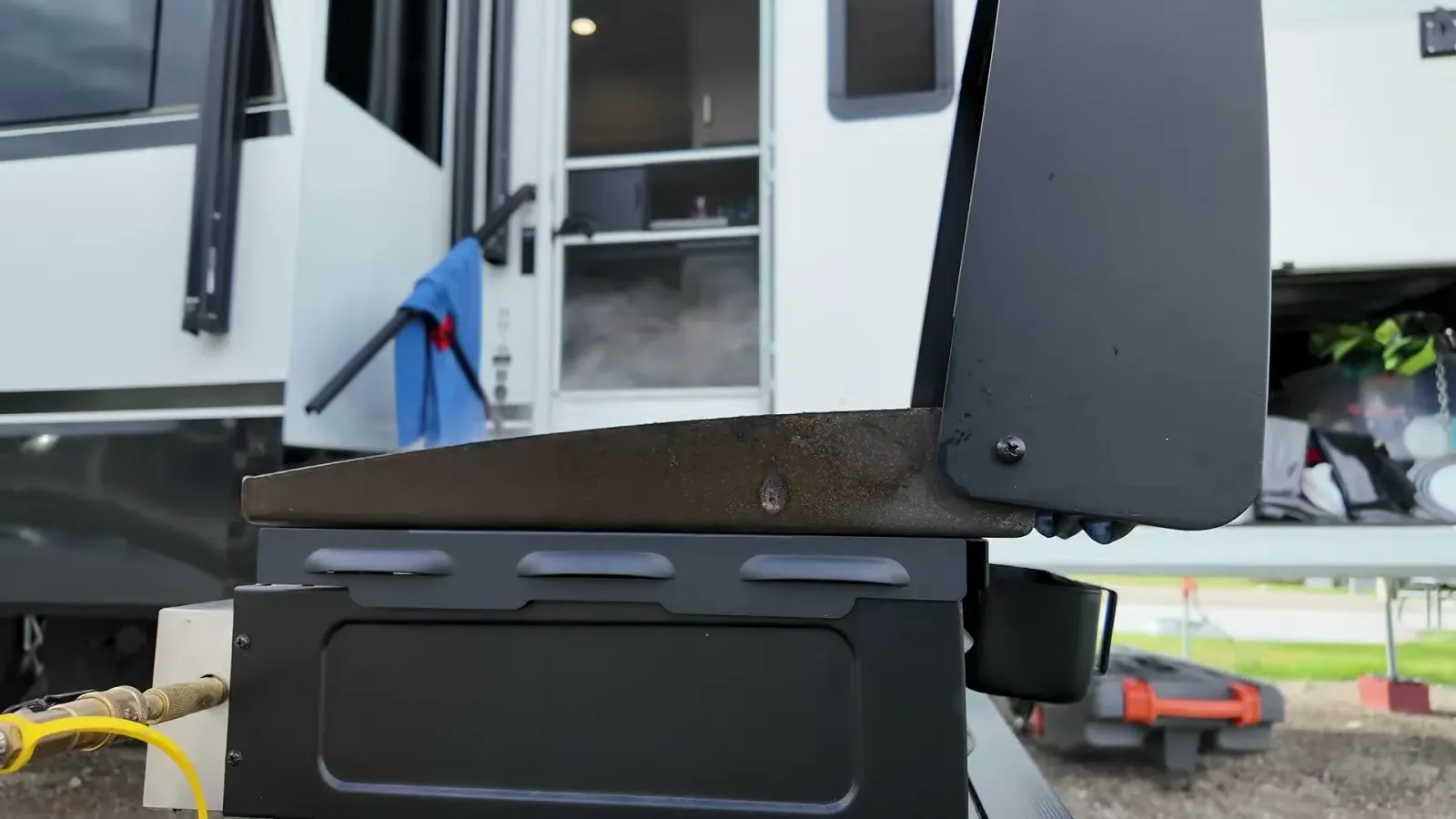 Blackstone griddle outside our Brinkley fifth wheel with the wind guard on the side next to the propane regulator
