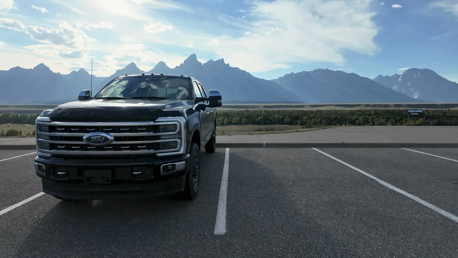 Our black Ford F-350 in an empty parking lot with the Teton Range rising behind it