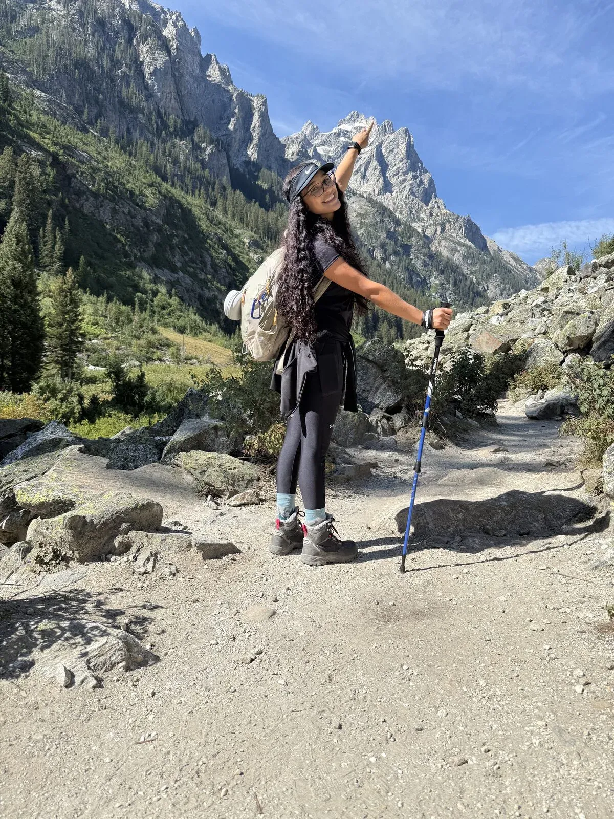Fabiola smiling and pointing up at a Teton peak from the Cascade Canyon trail