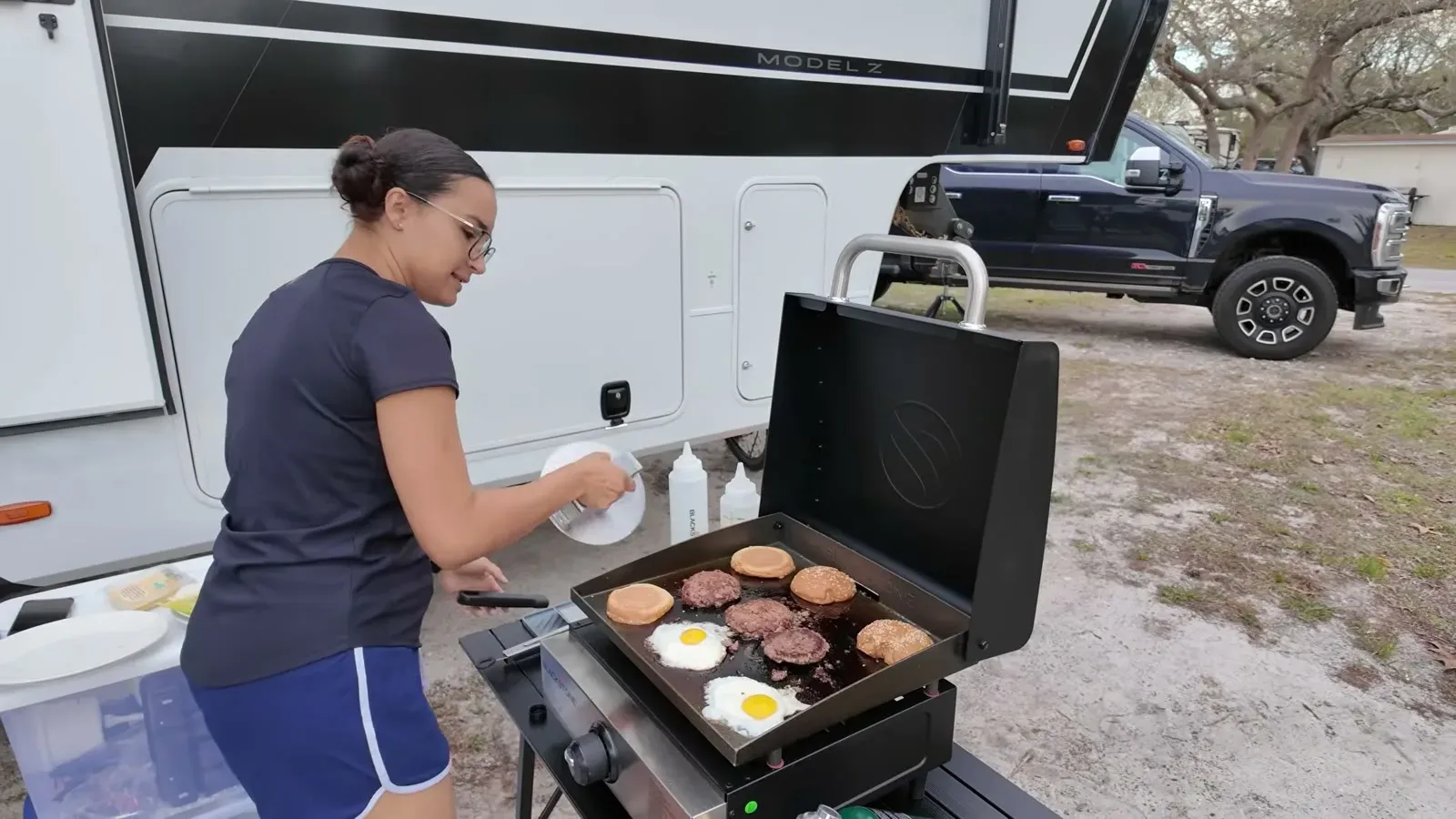 Fabiola works the 17 inch griddle with burger patties, fried eggs, and toasting buns all going at once beside the fifth wheel.