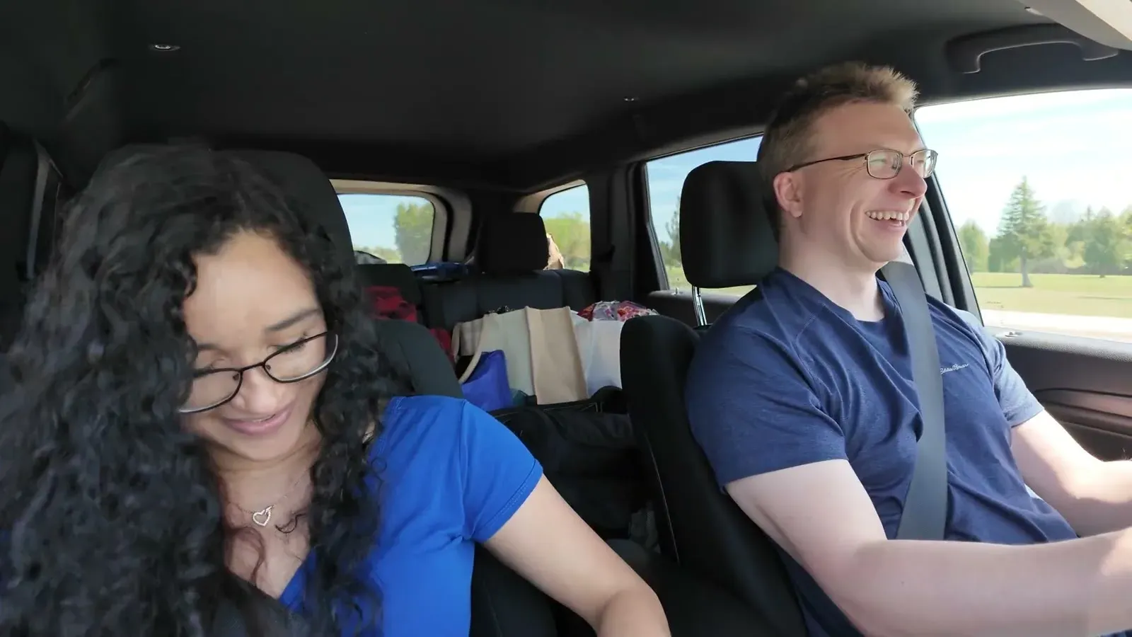 Nathan laughs behind the wheel while Fabiola grins in the passenger seat on a two-lane UP highway between stops.