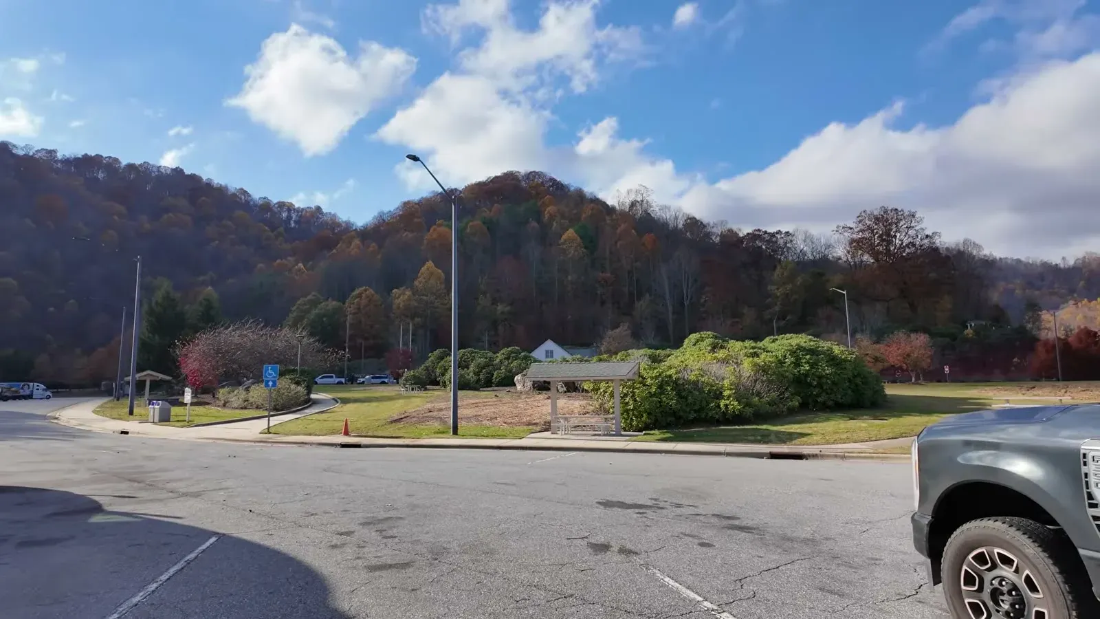 The North Carolina welcome center tucked against fall-colored mountains, with the truck parked at the edge of the lot.