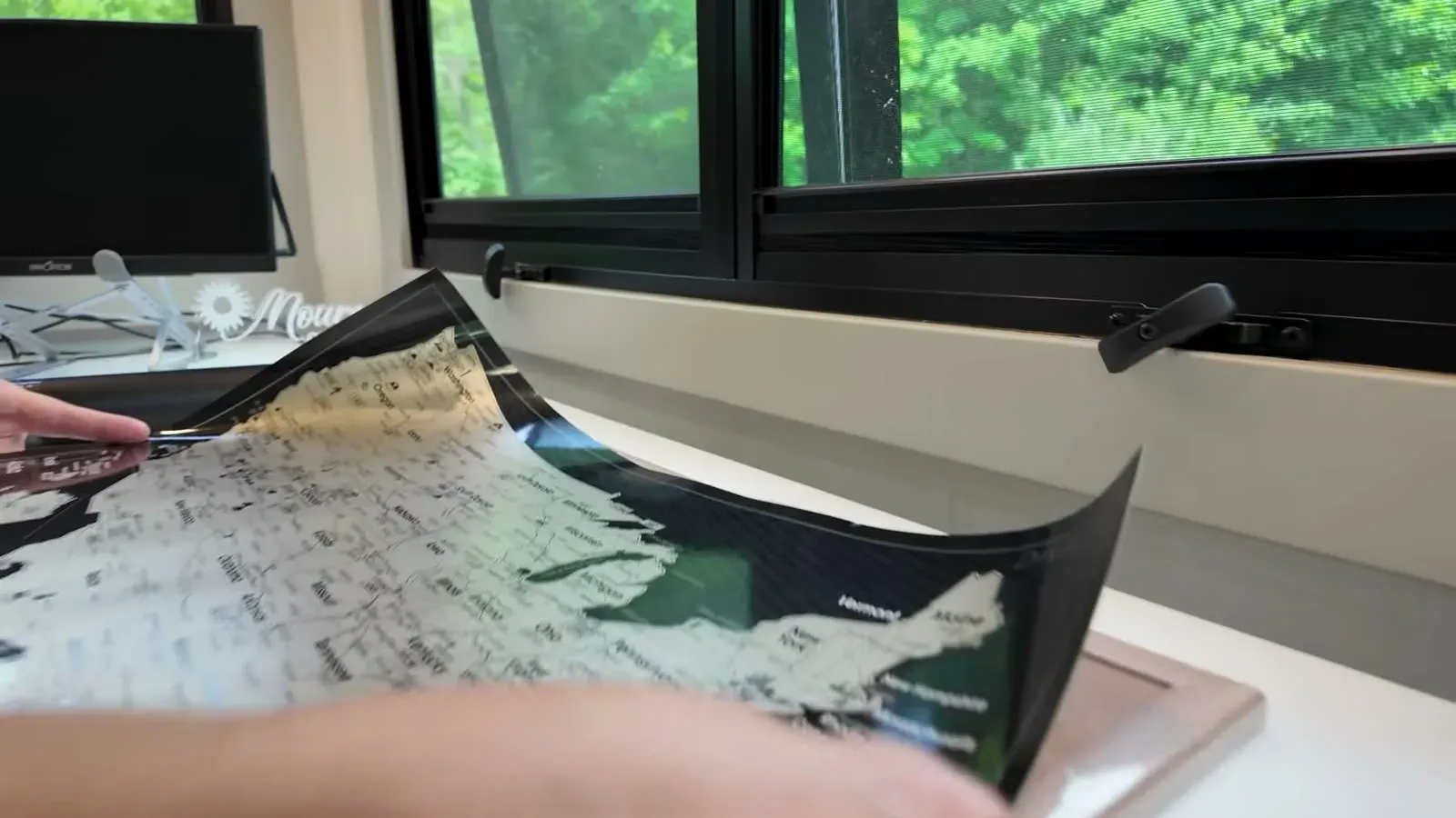 Unrolling the scratch-off U.S. travel map on the table inside the rig.