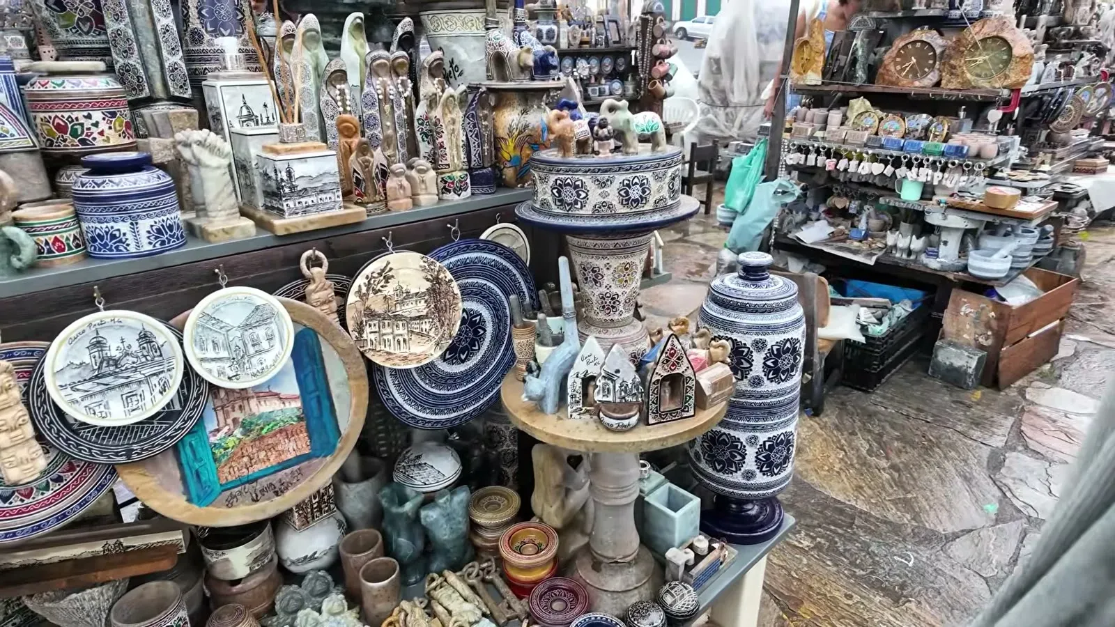 A market stall stacked with hand-carved and painted soapstone plates, pots, and trinkets at Ouro Preto's pedra-sabao market.