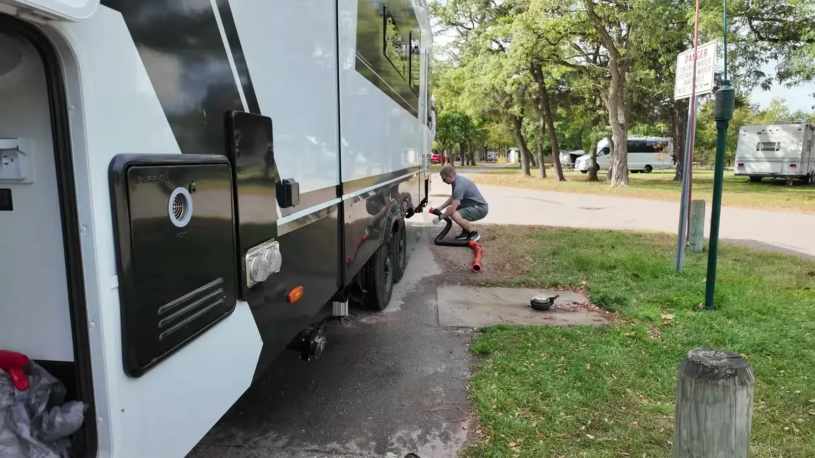 Crouched at the campsite sewer connection working through the dump-and-flush routine before pulling out.