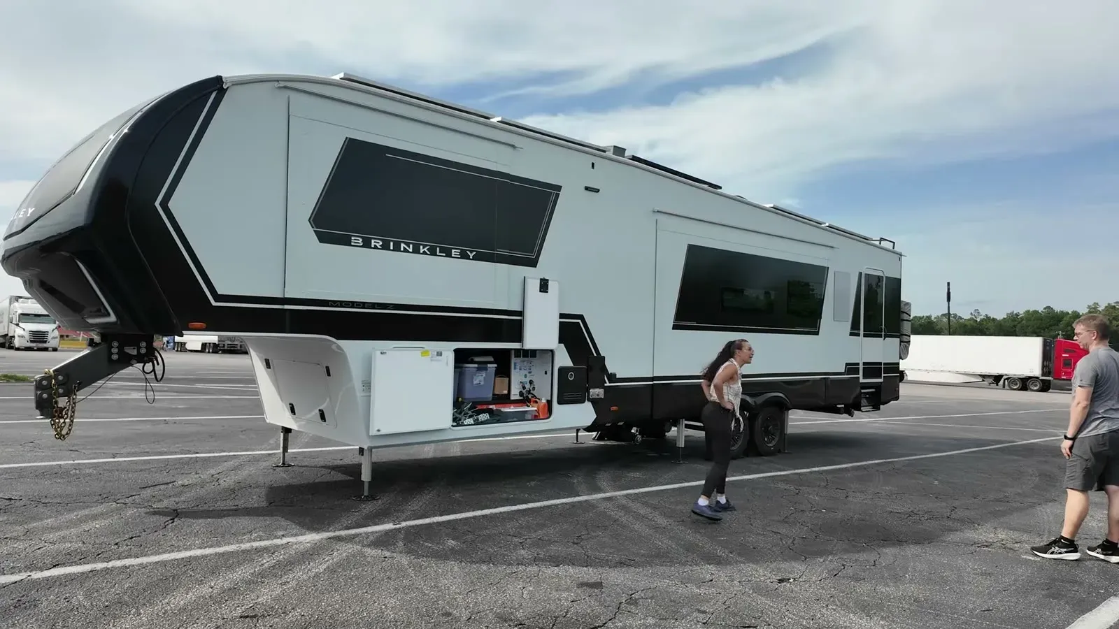 The Brinkley unhitched in the sloped truck stop lot, front landing gear cranked high while Fabiola checks the wheels.