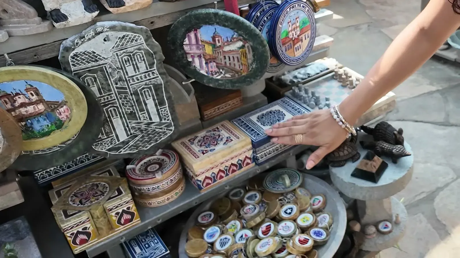 Carved soapstone plates, boxes, and trinkets stacked on a stall at the Ouro Preto stone market.