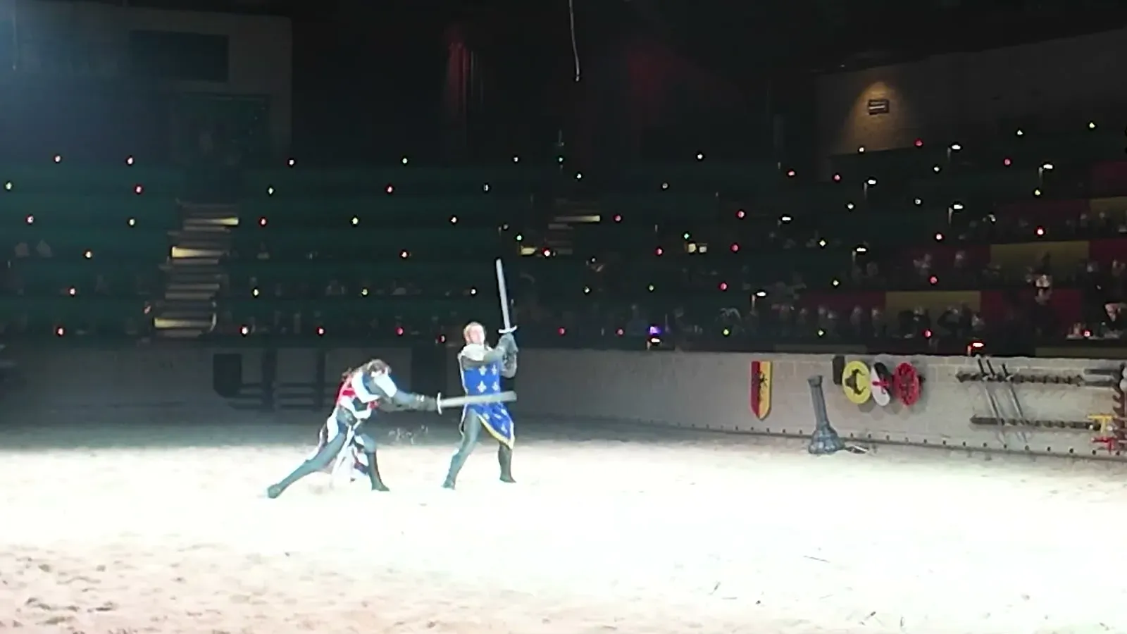Two knights trade sword blows in the middle of the arena while the crowd watches from the dark stands.