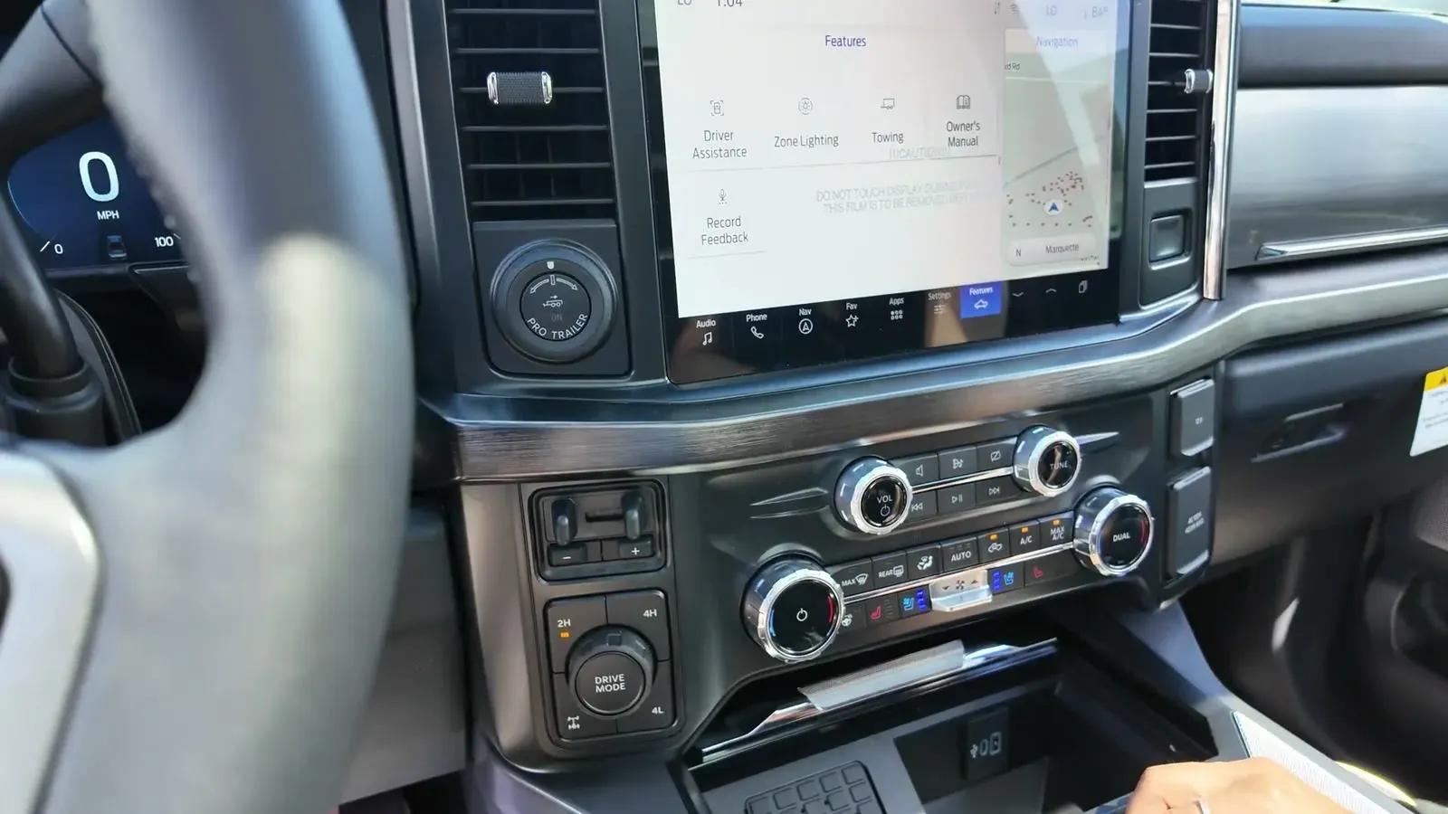 The F-350's dash from the driver's seat, wide touchscreen up top and real climate dials below it.