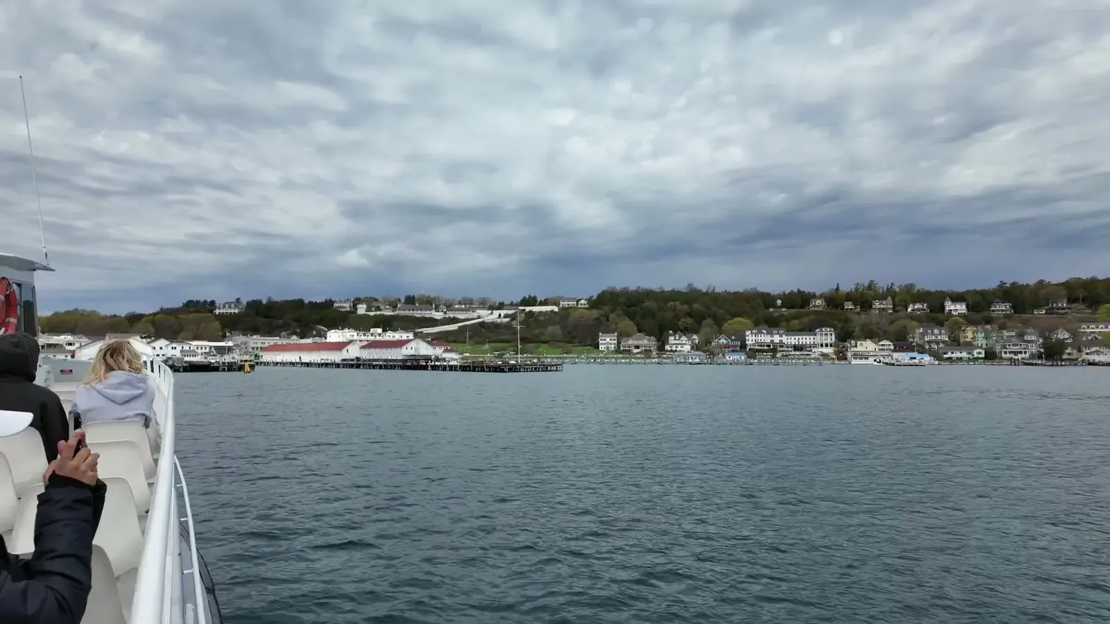 Mackinac Island's harbor and waterfront coming into view from the ferry deck under a moody spring sky.