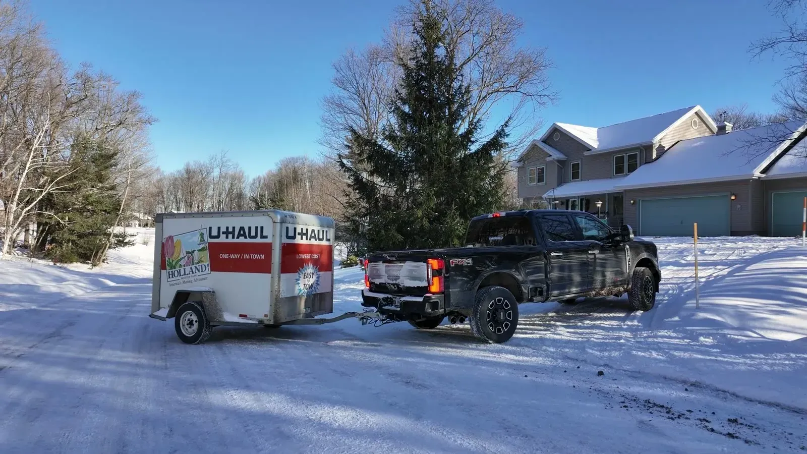 Our black F350 hitched to the U-Haul trailer on a snowy driveway in Marquette, ready for loading.