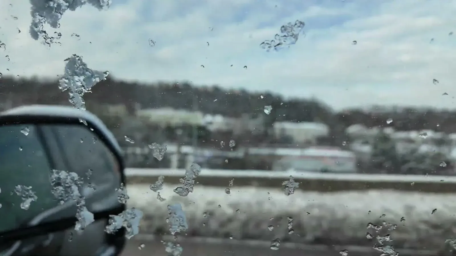 Snow on the highway seen through an icy truck window