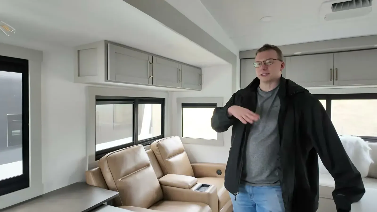 Nathan standing by the leather theater seats and wraparound windows in the Brinkley Model Z 3100 living area.