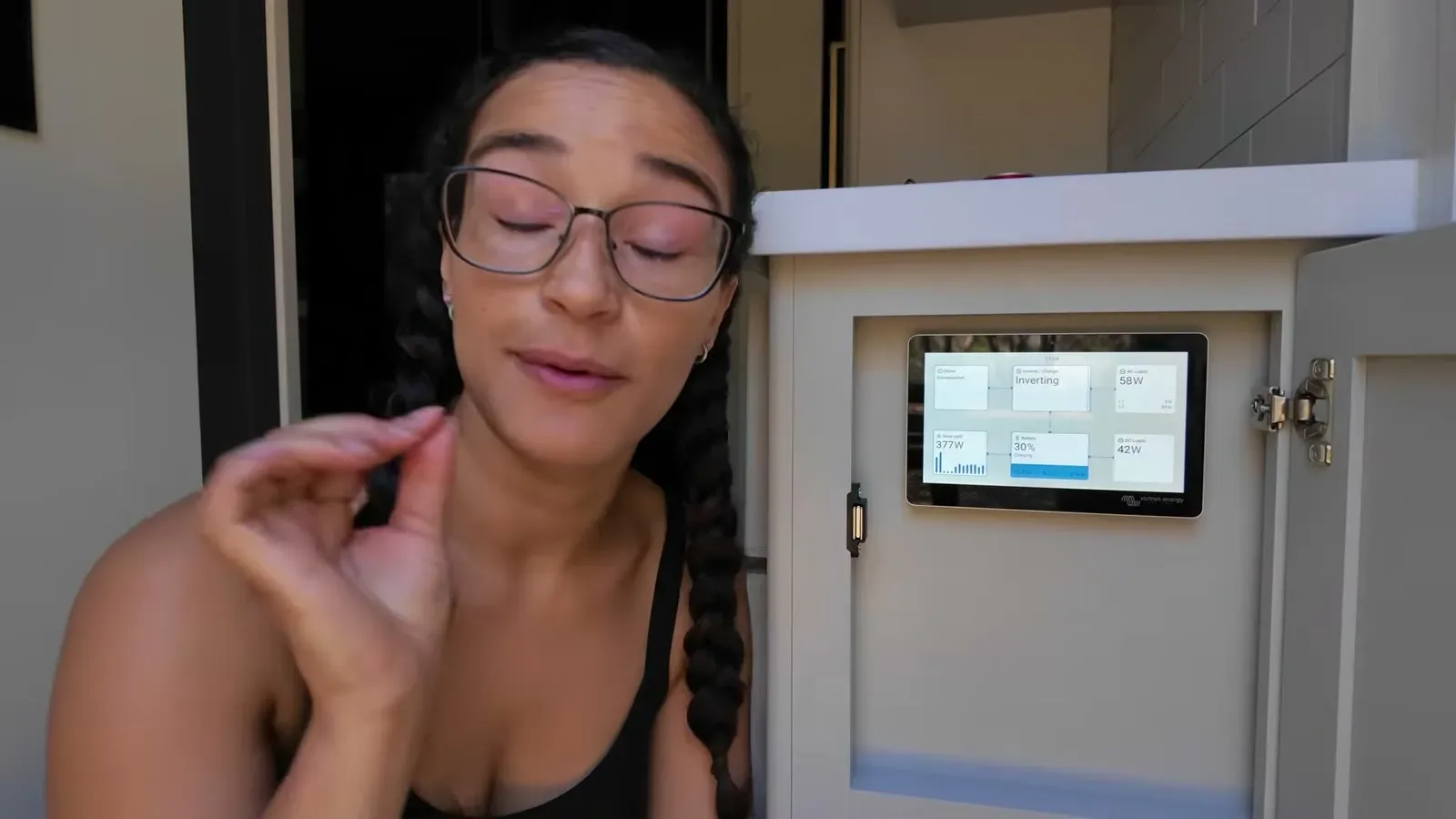 Fabiola checking the battery numbers on the RV's control panel inside its cabinet.