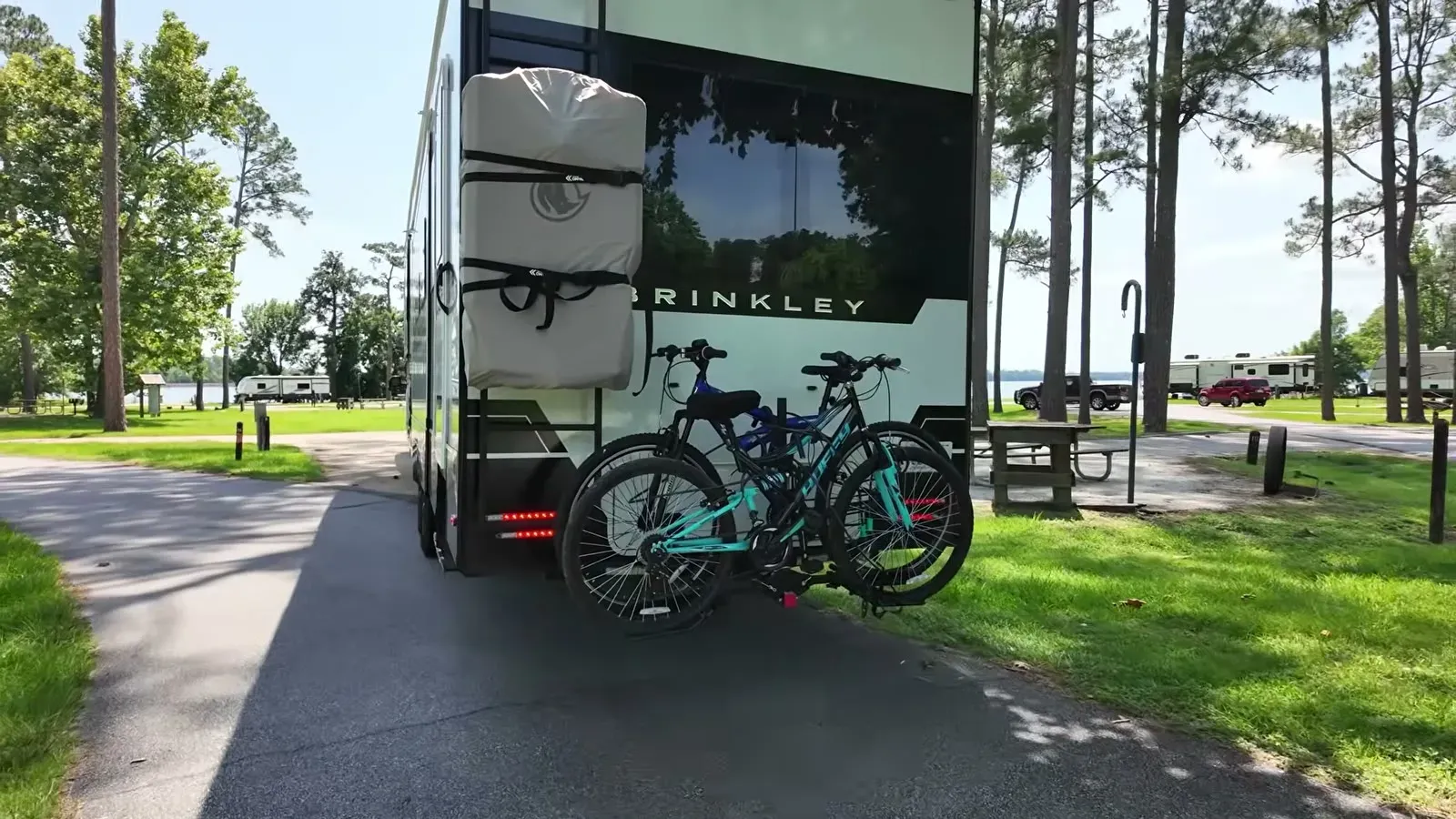 Our fifth wheel, bikes still on the rack, rolling into the pull-through site at East Bank with Lake Seminole through the pines.