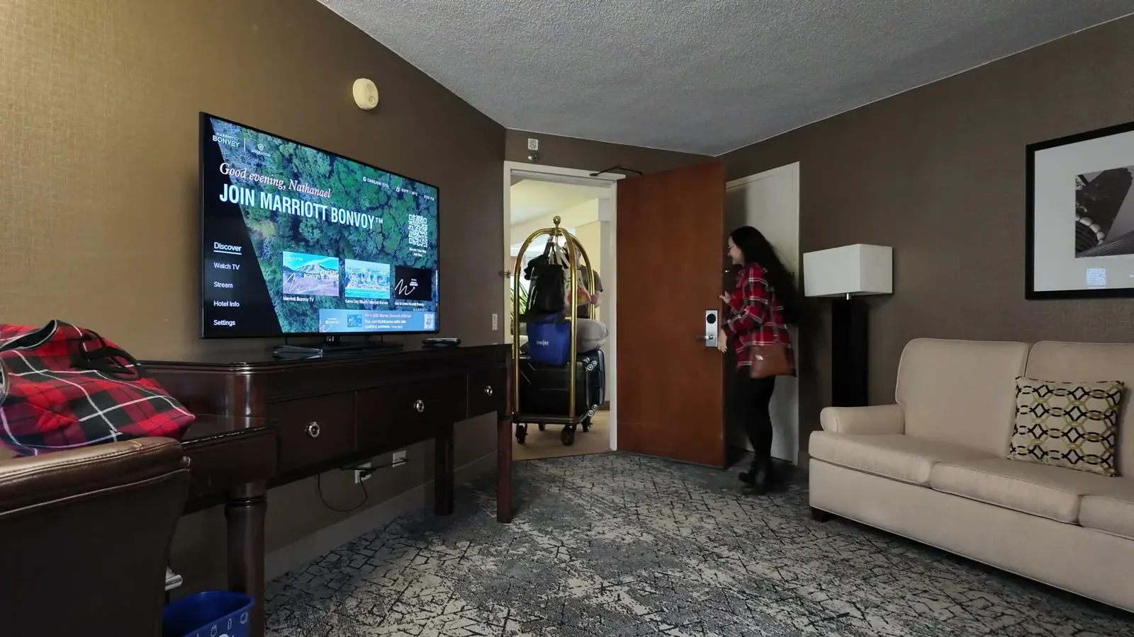 Our loaded luggage cart parked in the living room of the suite while Fabiola heads through the door, proof of how much we packed for one week.