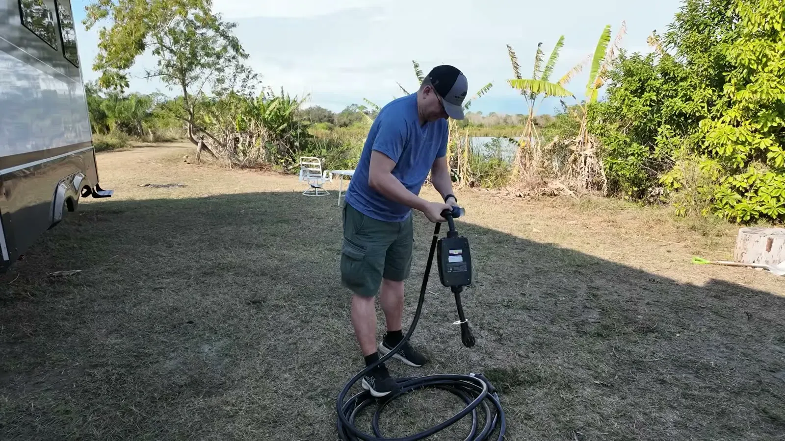 Nathan coils the power cord at our Hipcamp farm site outside Tampa, banana trees still standing behind the rig.