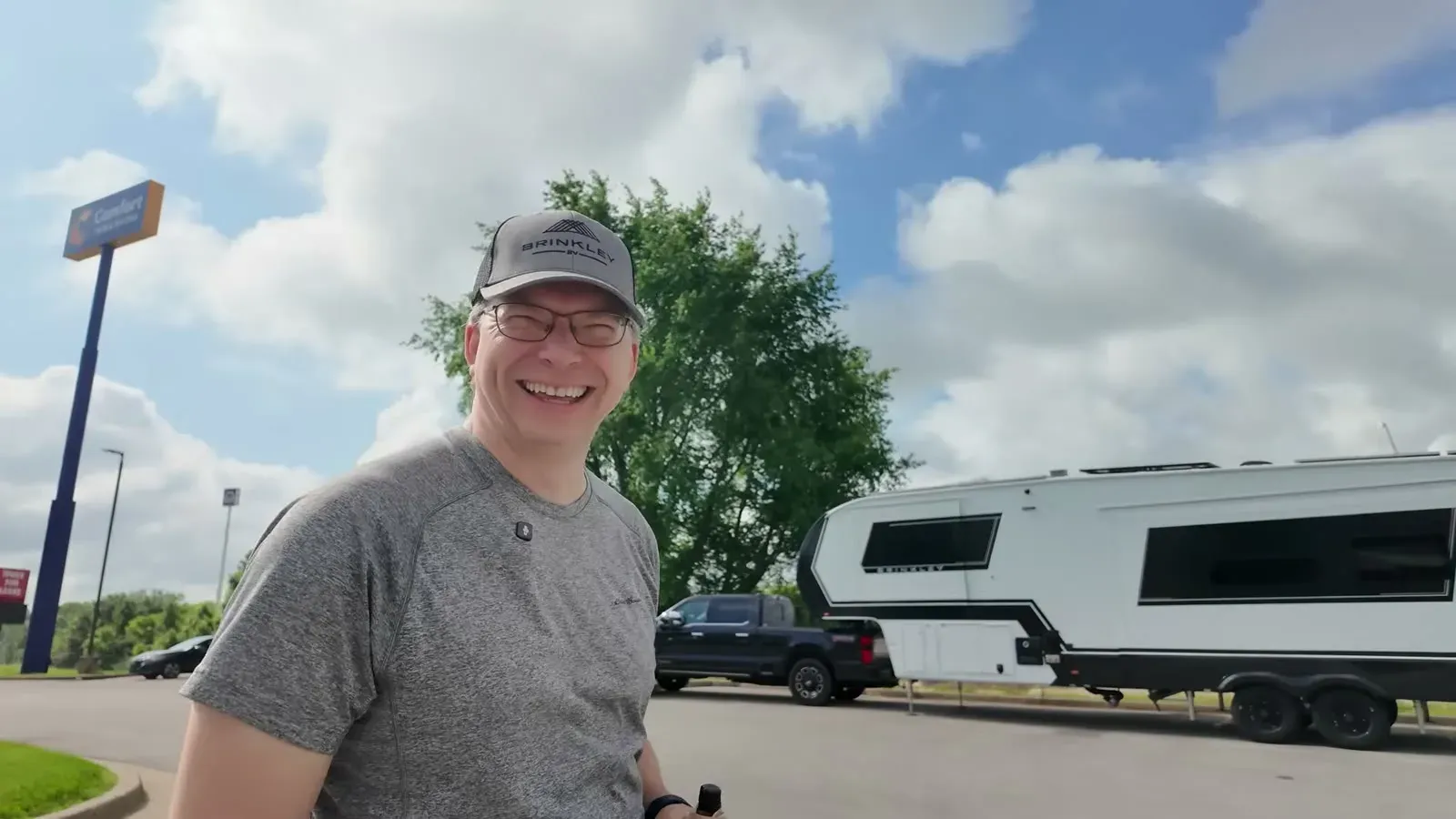 Nathan grinning in the Cracker Barrel parking lot with our fifth wheel and the black truck parked close behind it.